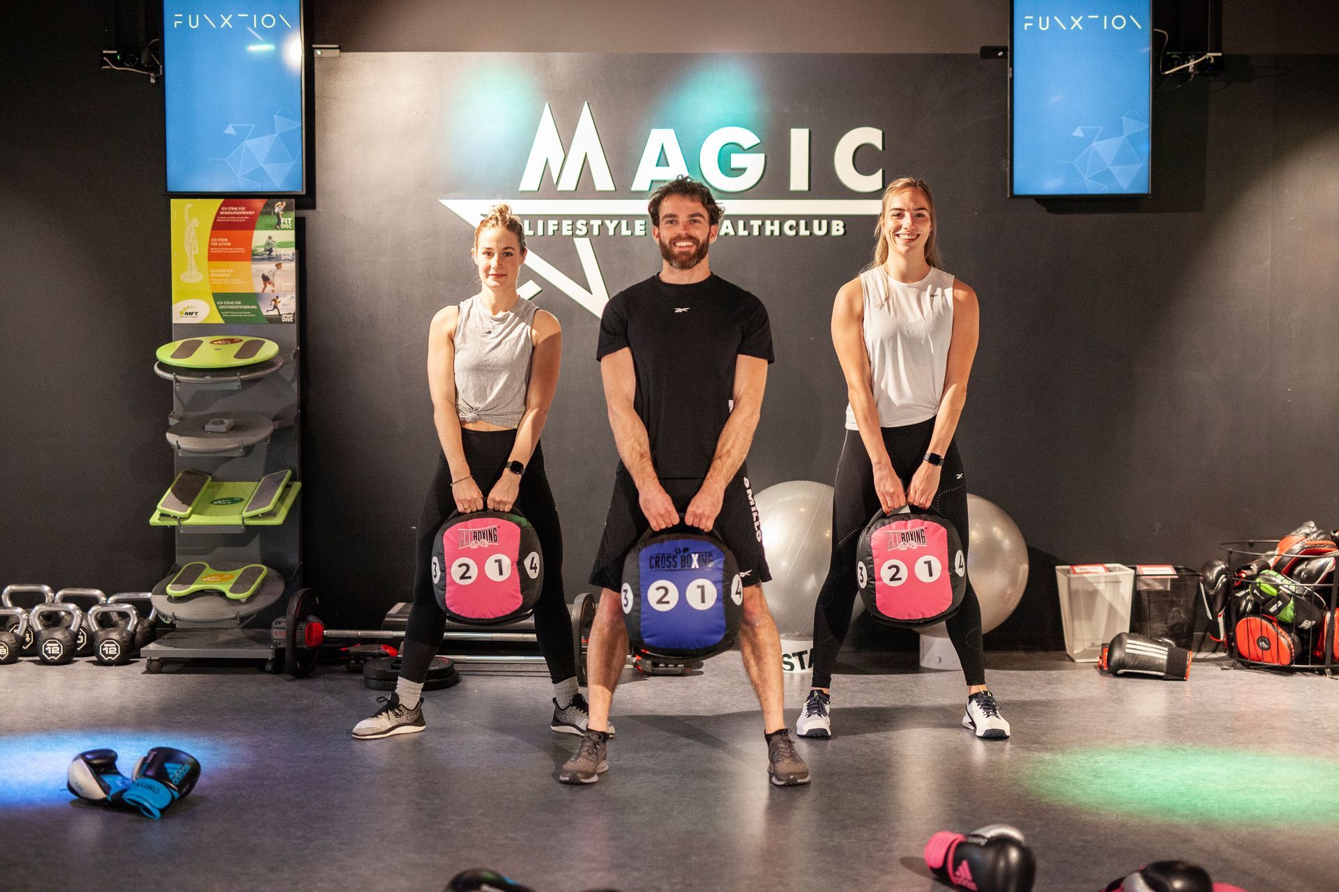 Een man en twee vrouwen houden gewichten vast in een sportschool.