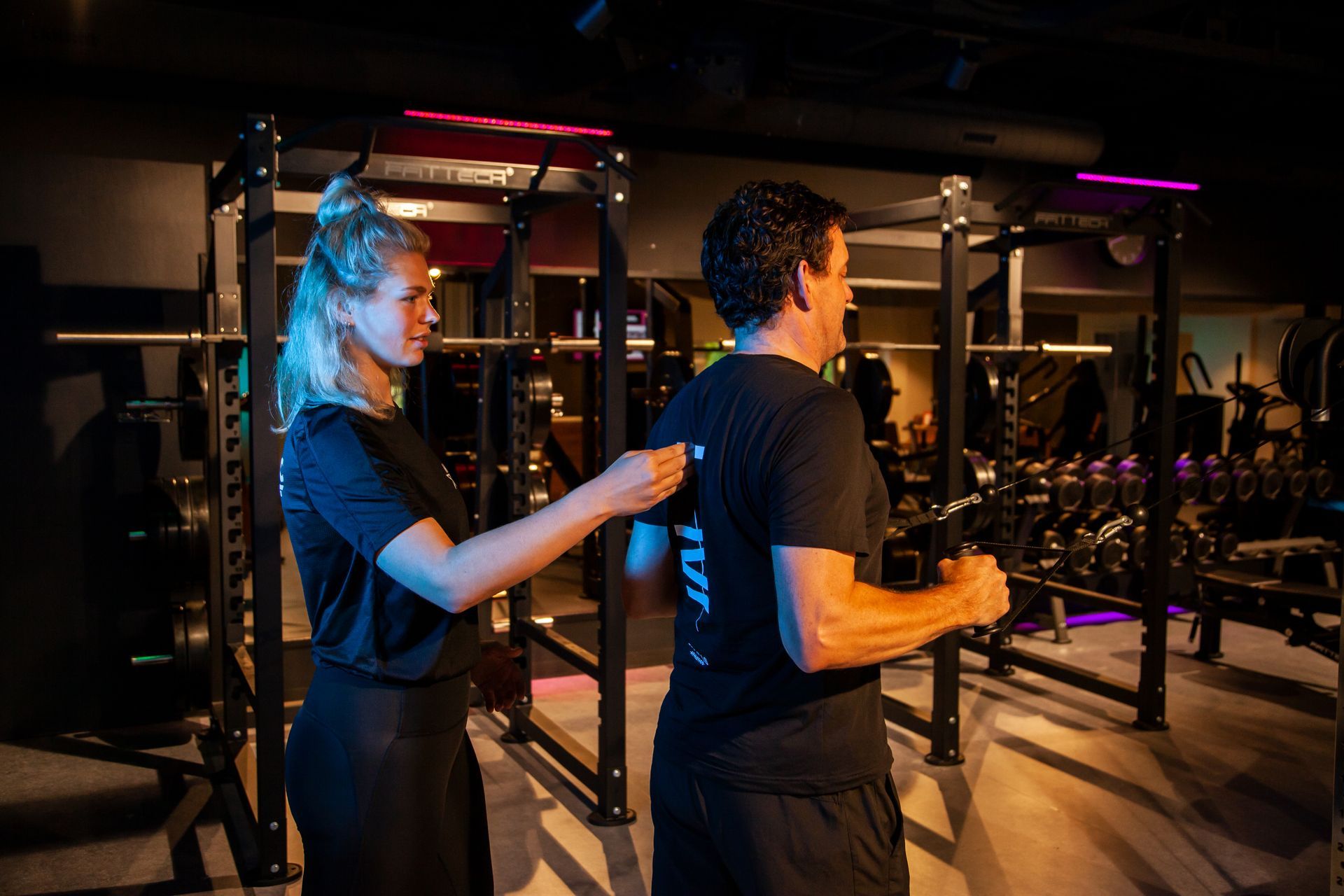 Een vrouw meet de rug van een man in een sportschool.