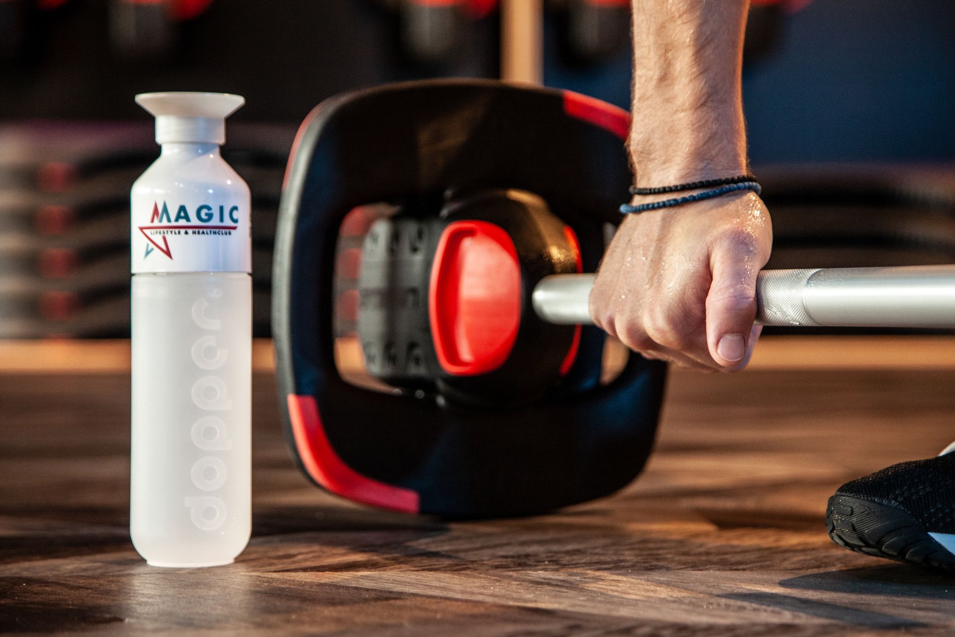 Een persoon houdt een halter vast naast een fles water.