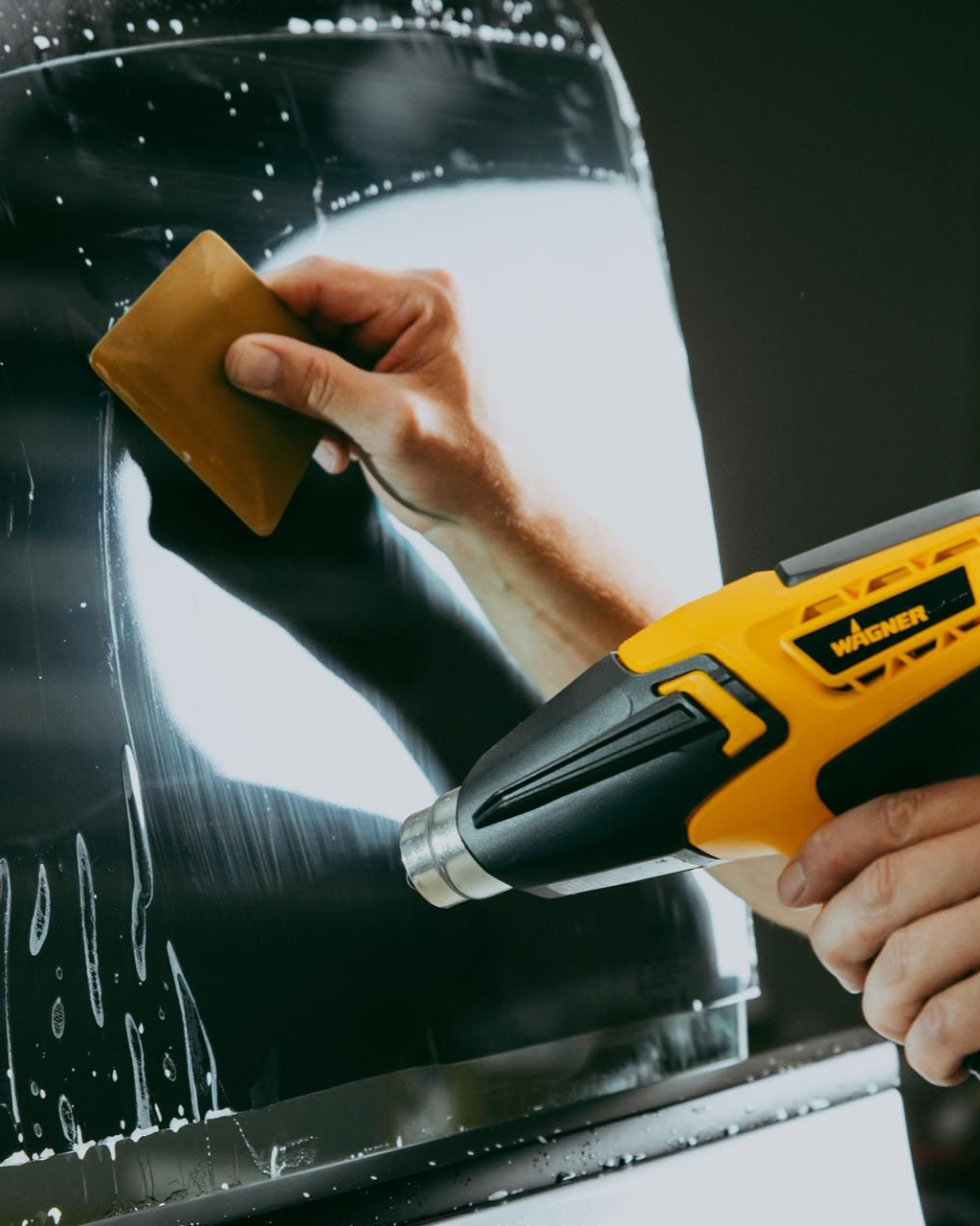 A person is cleaning a car window with a squeegee.