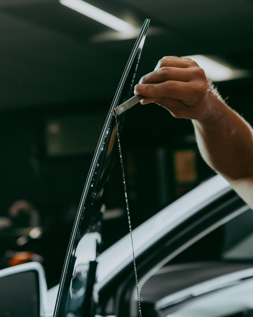 A person is cleaning a car window with a yellow sponge.