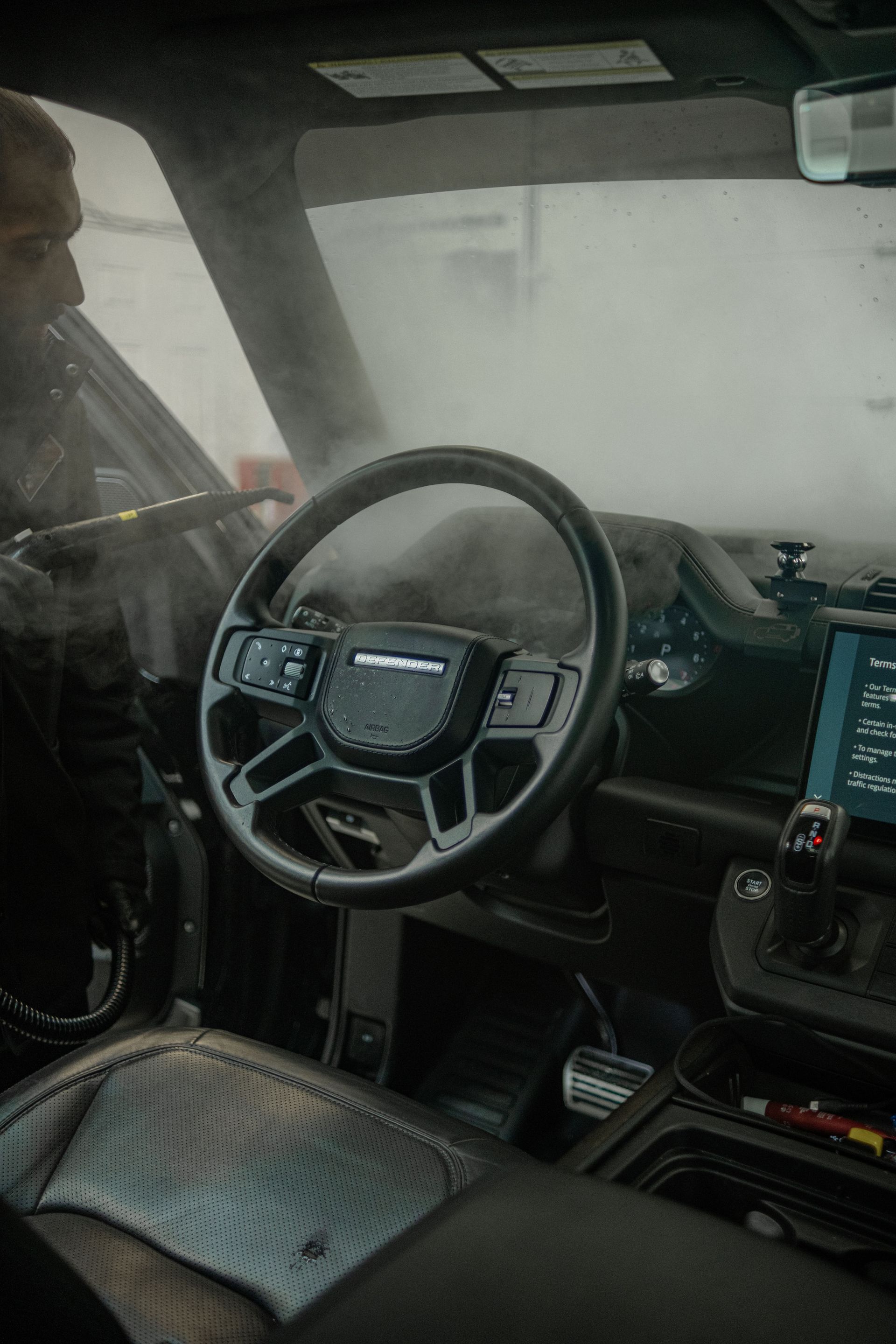 A person wearing black gloves is polishing a black car