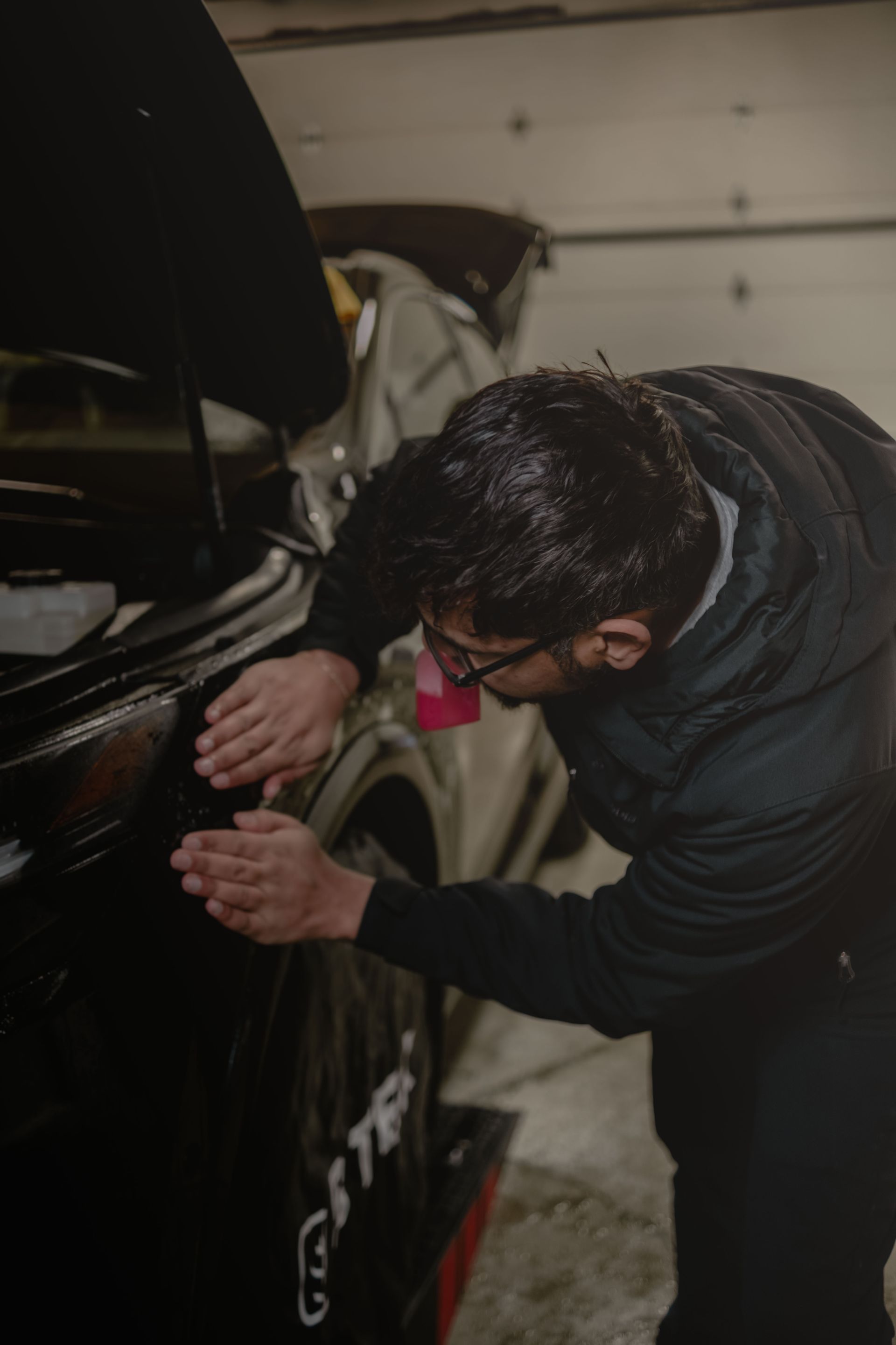 A person is cleaning a blue car with an orange towel
