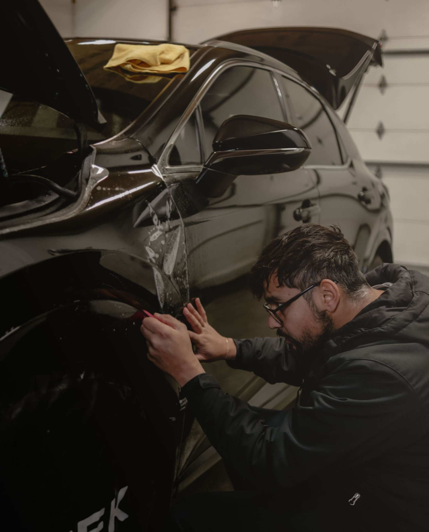 A person is wrapping a car with clear plastic