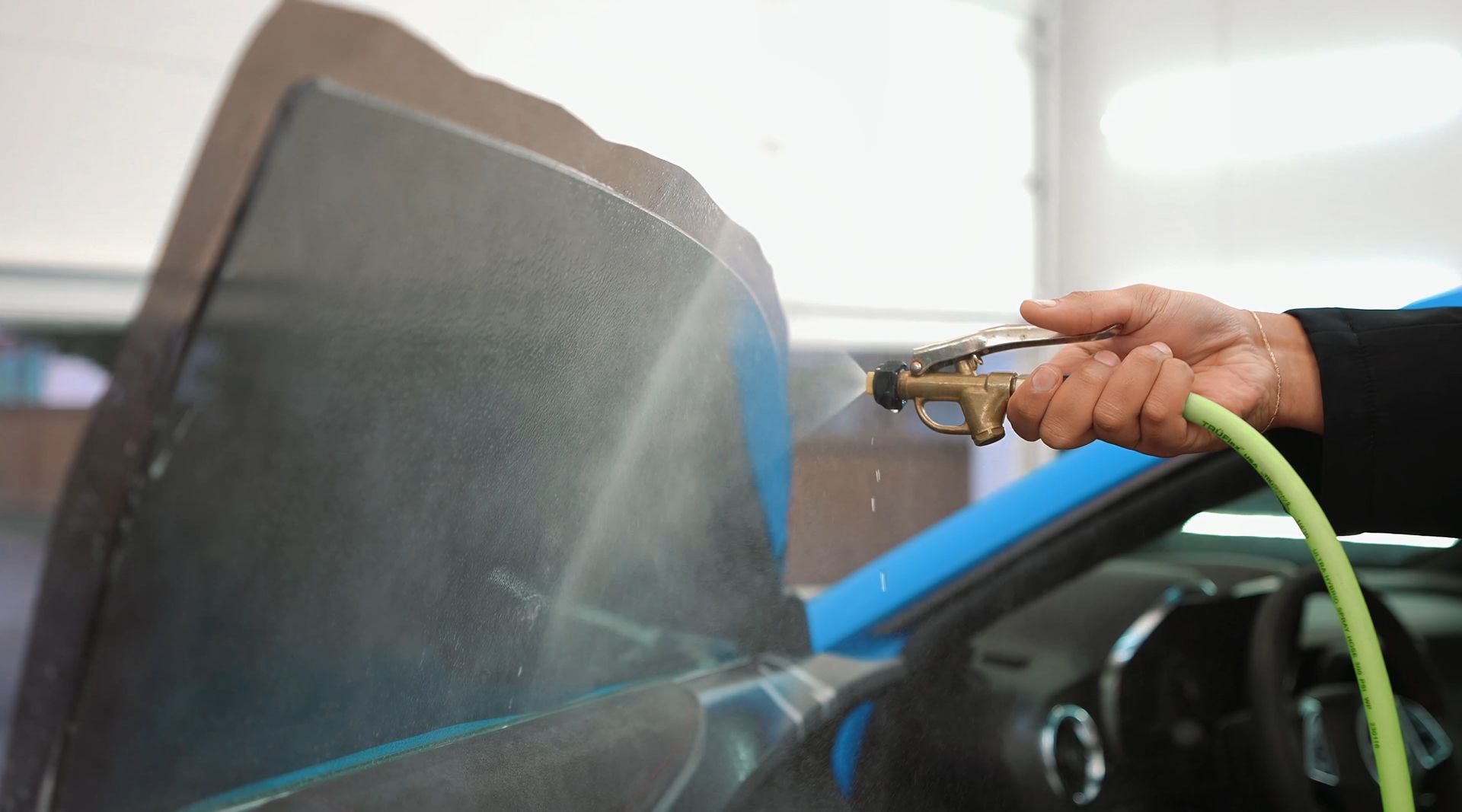 A man is sitting on a stool in front of a car.