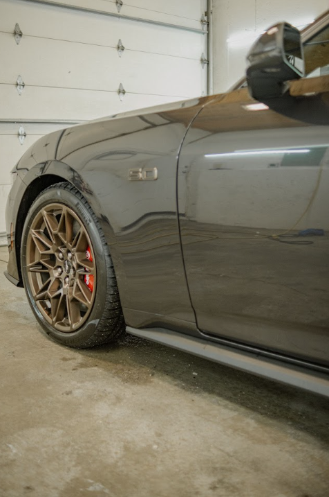 A black car is parked in a garage next to a garage door.
