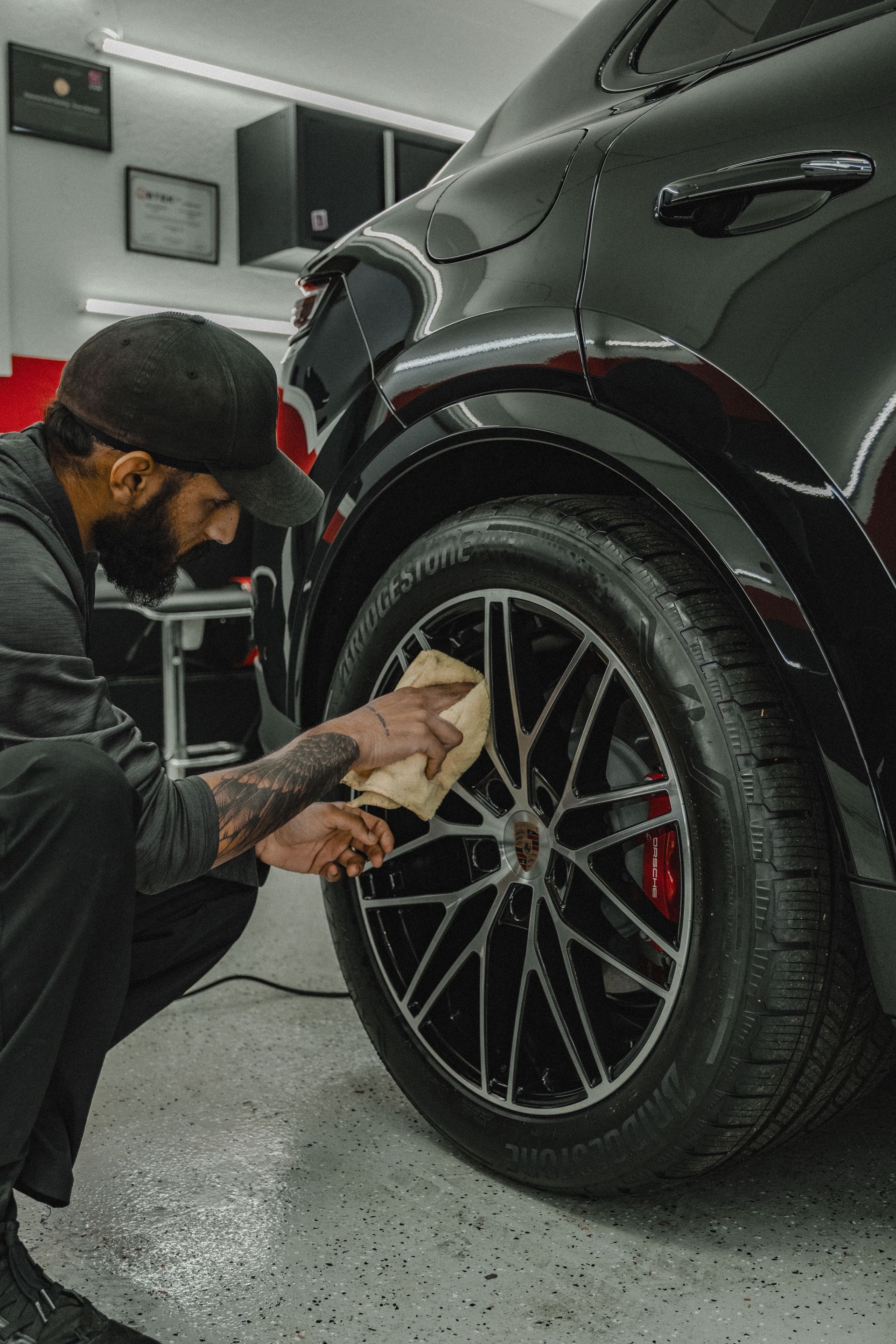 A person is polishing the hood of a blue car.