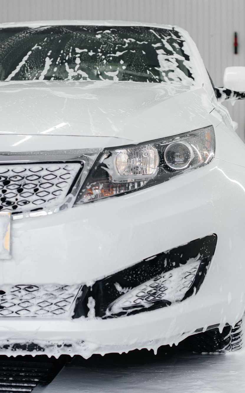 A person wearing black gloves is polishing a black car