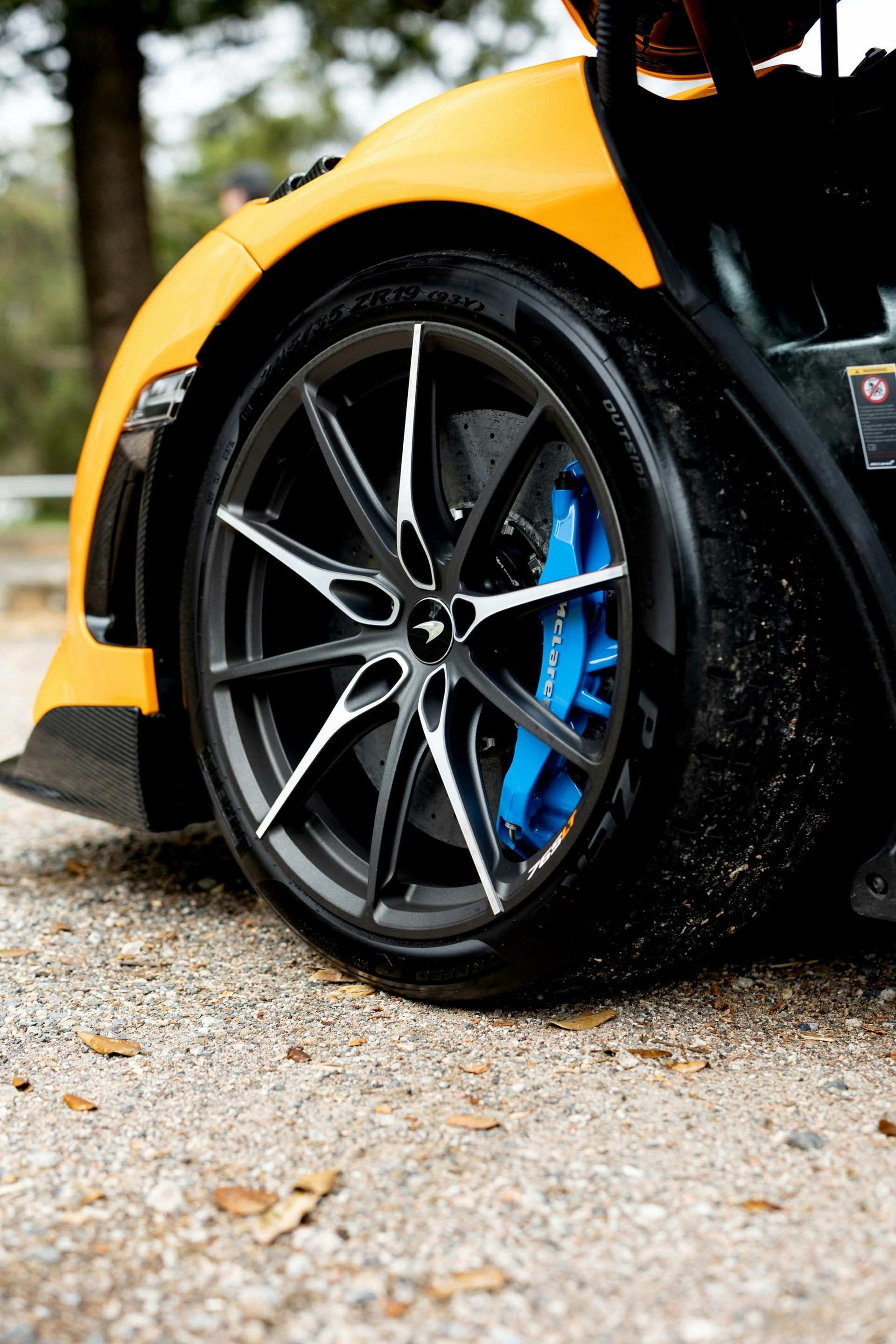 A person is cleaning a blue car with an orange towel
