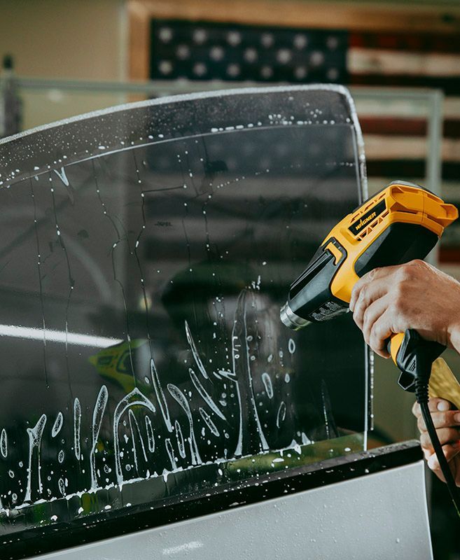 A person using a heat gun to apply window tint.