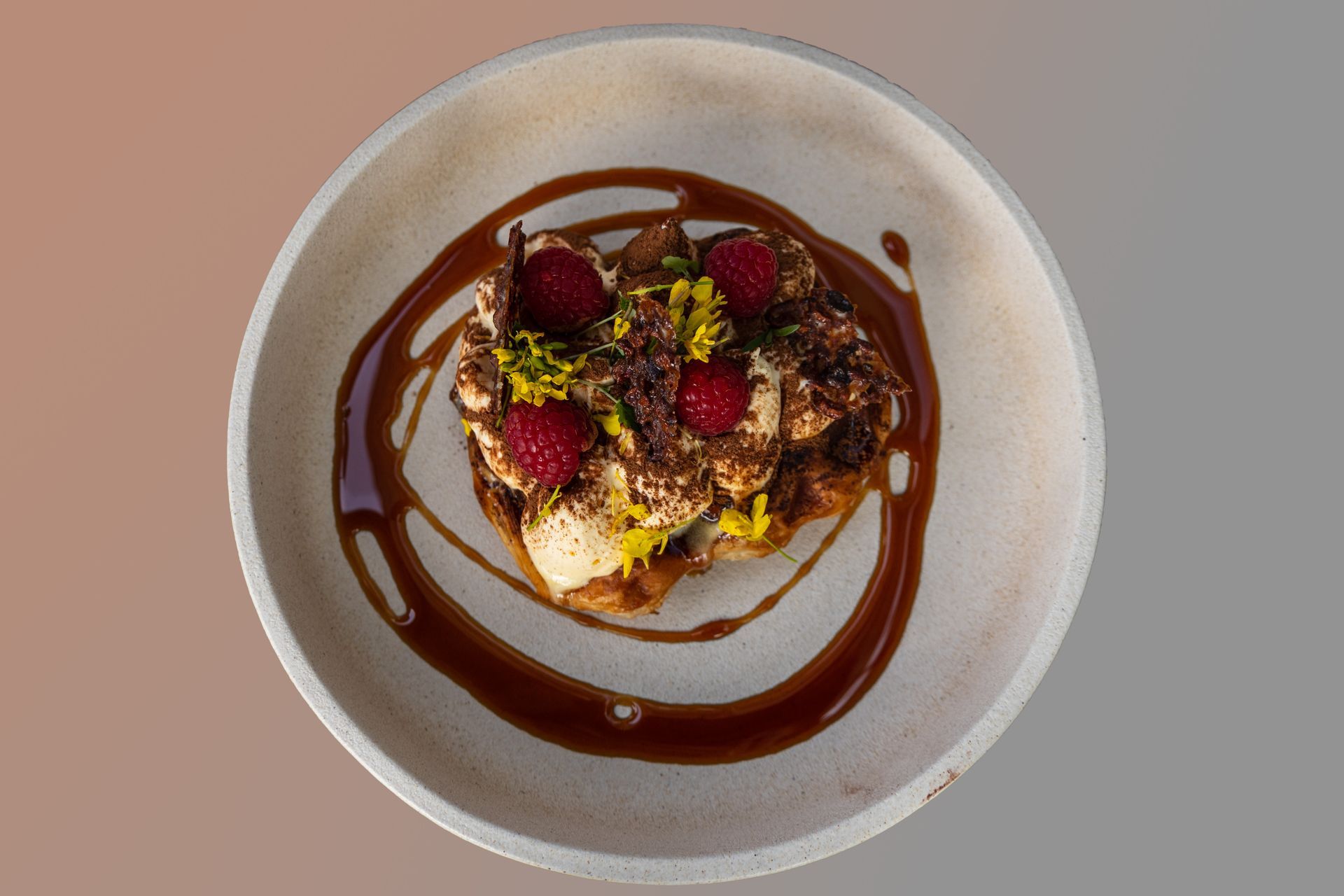A white plate topped with a dessert with raspberries and chocolate sauce.