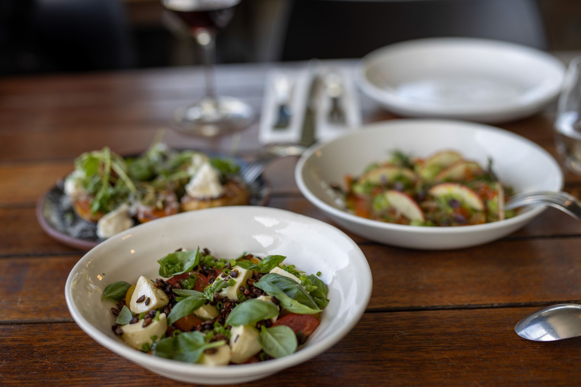 Three bowls of food are sitting on a wooden table.