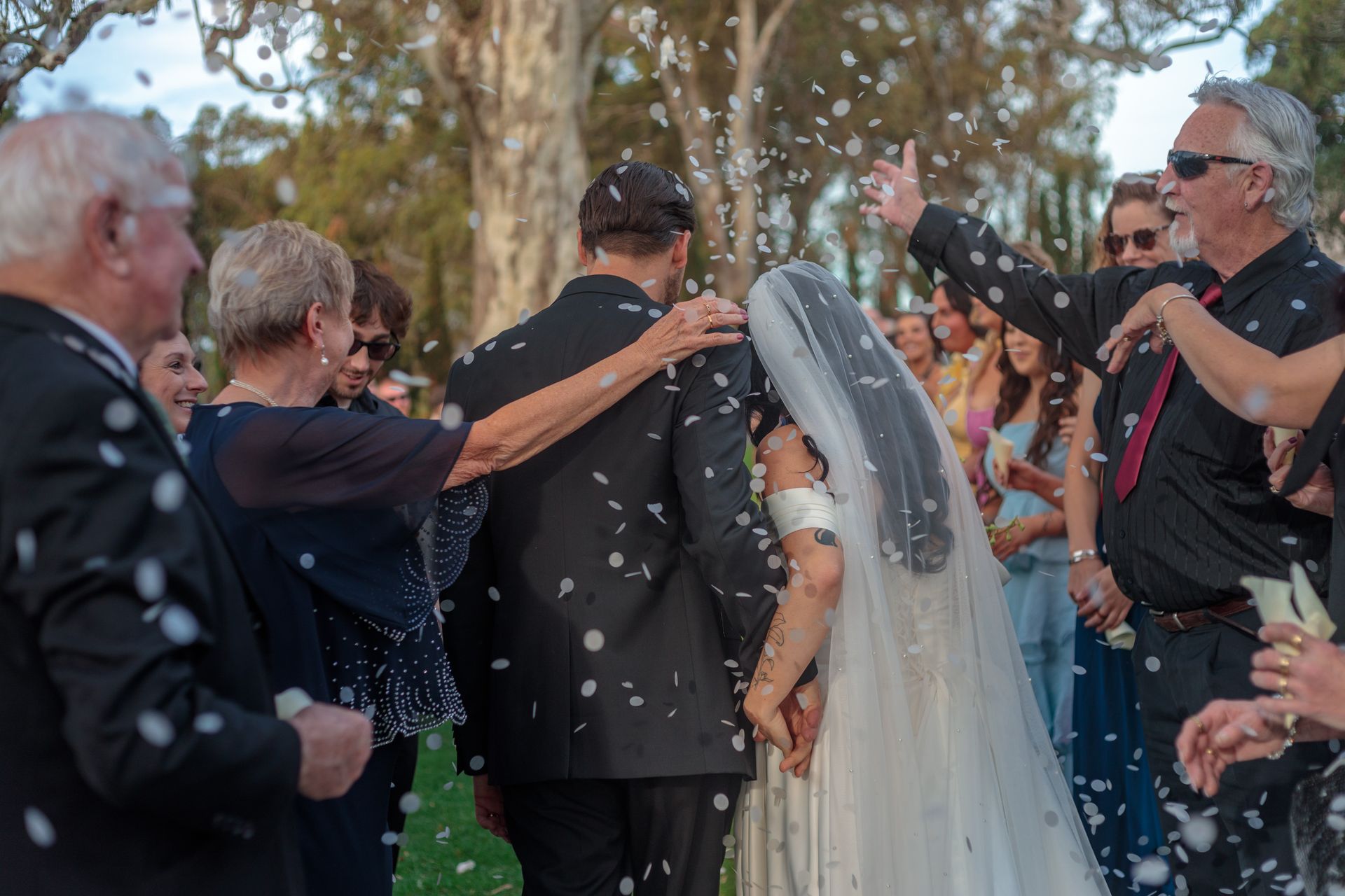 A bride and groom are being showered with confetti at their wedding.