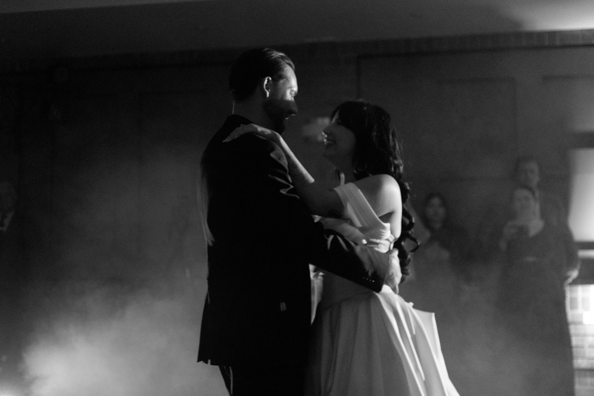 A bride and groom are dancing in a black and white photo.