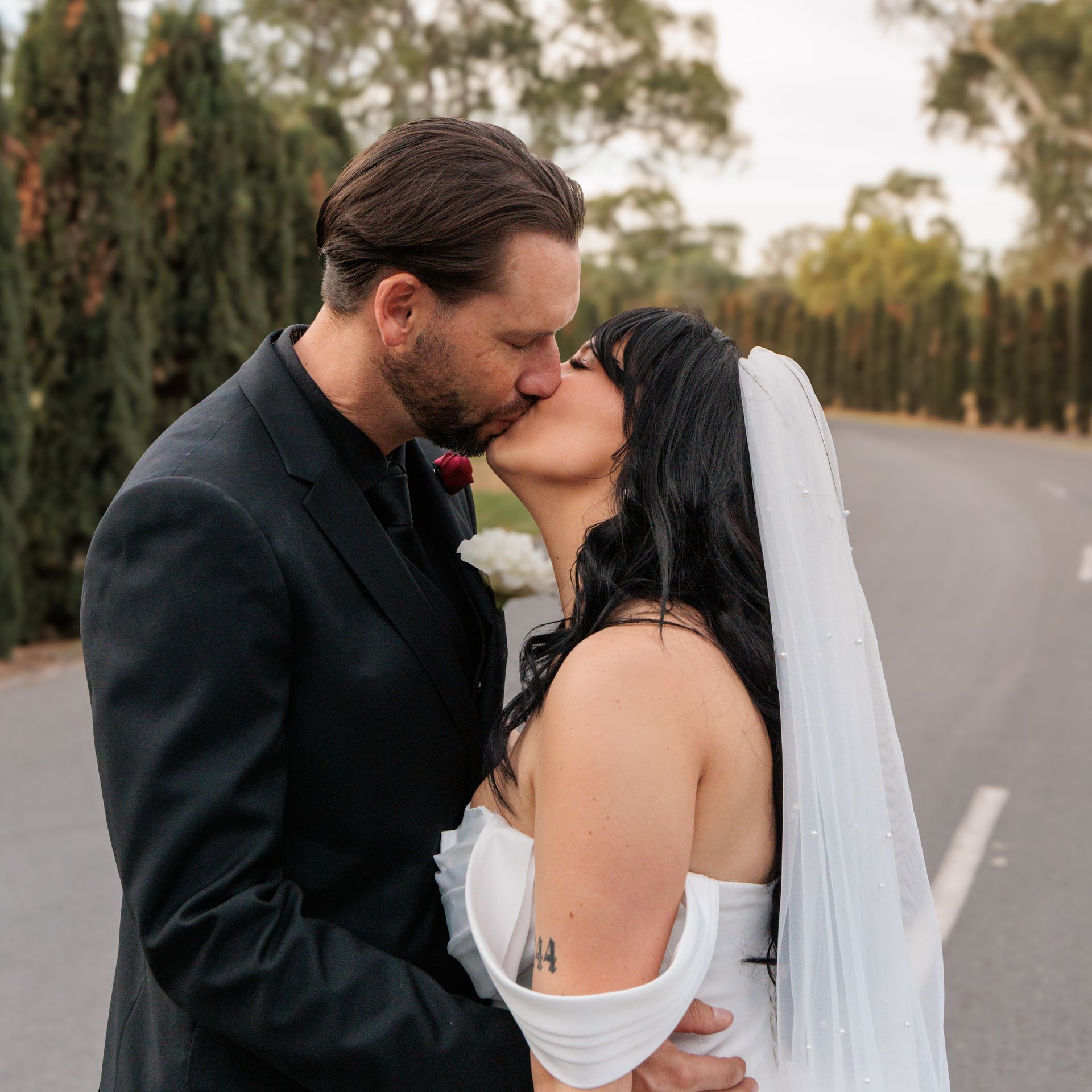 A bride and groom kissing on the side of a road