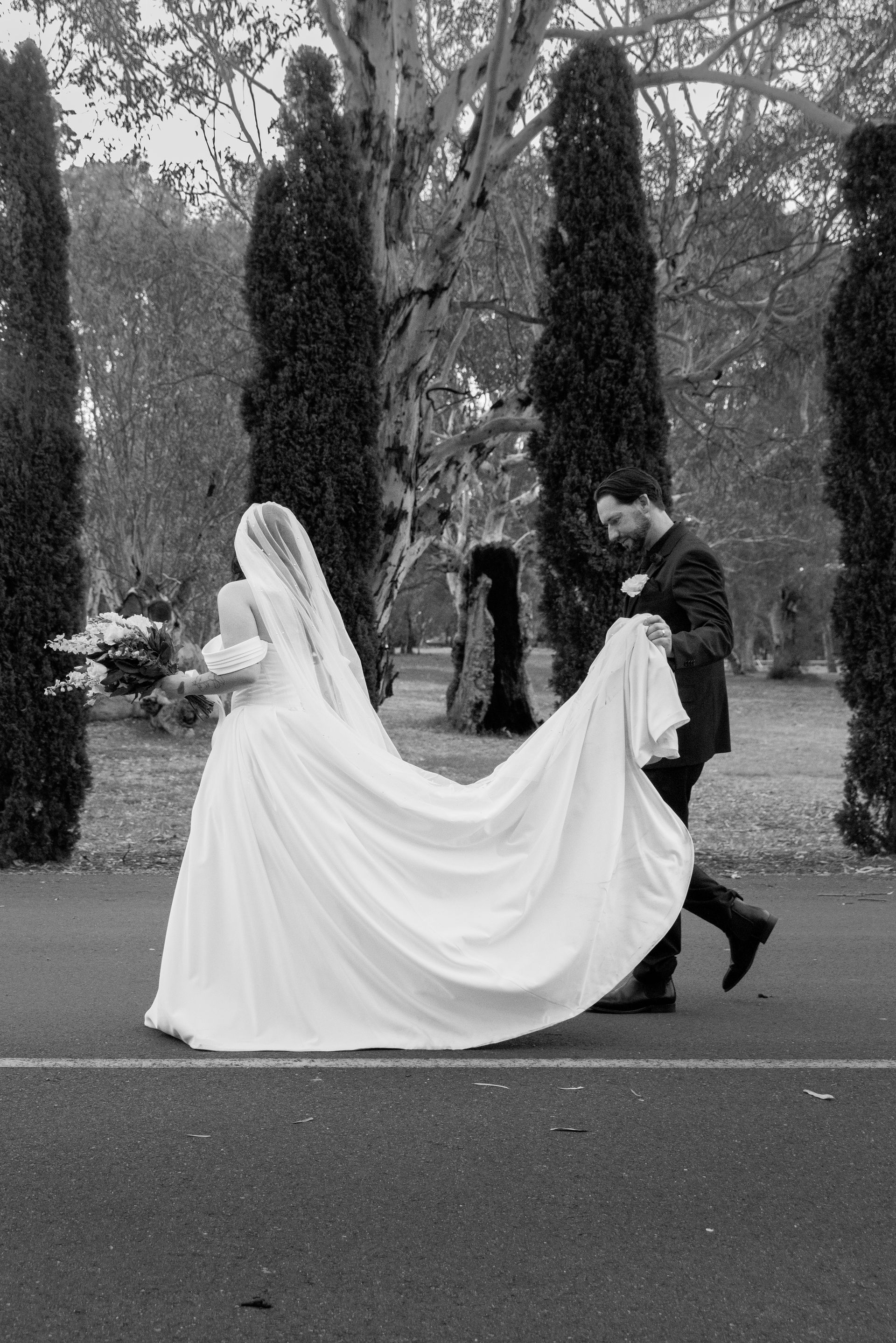 A black and white photo of a bride and groom walking down the street.