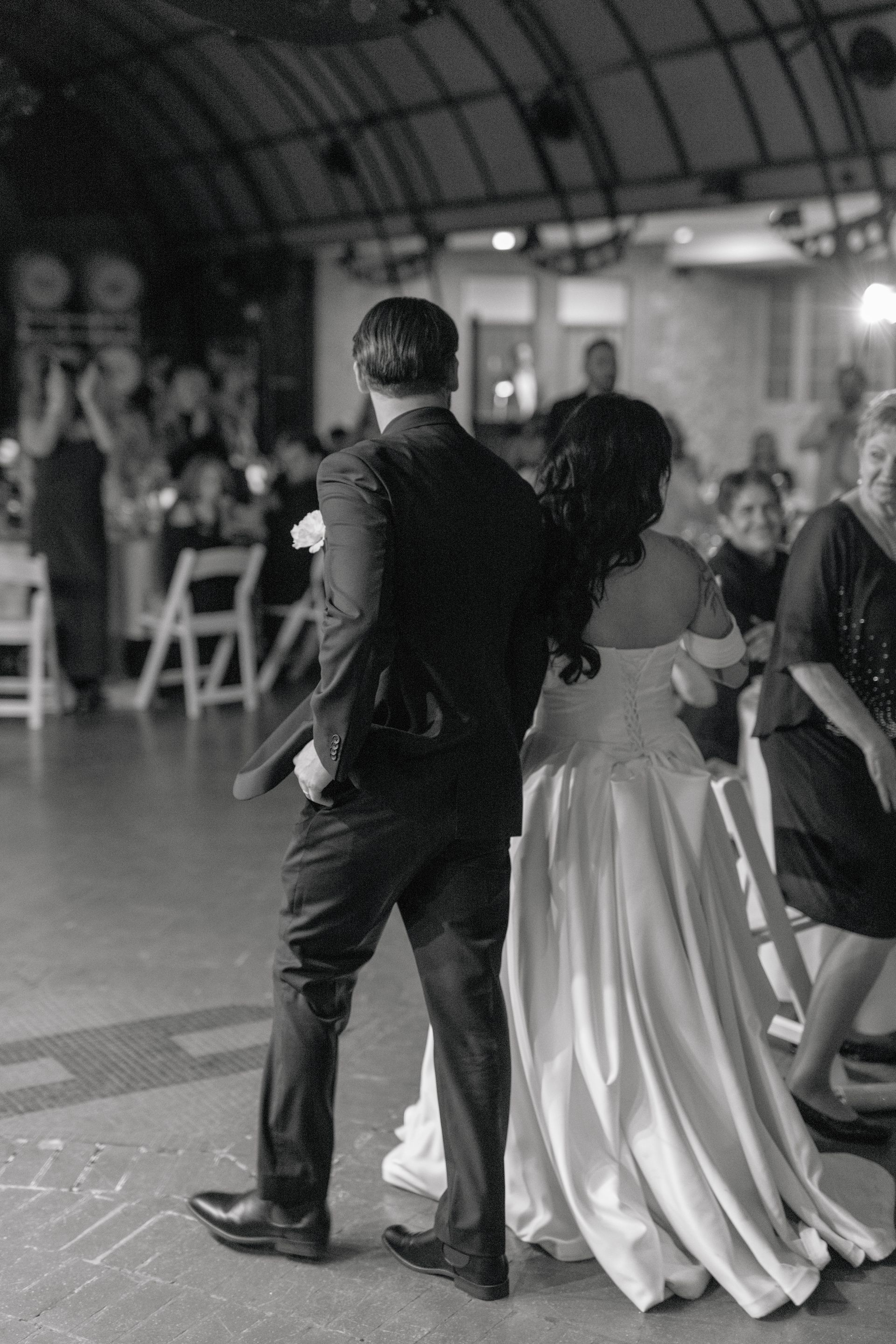 A black and white photo of a bride and groom dancing at a wedding reception.