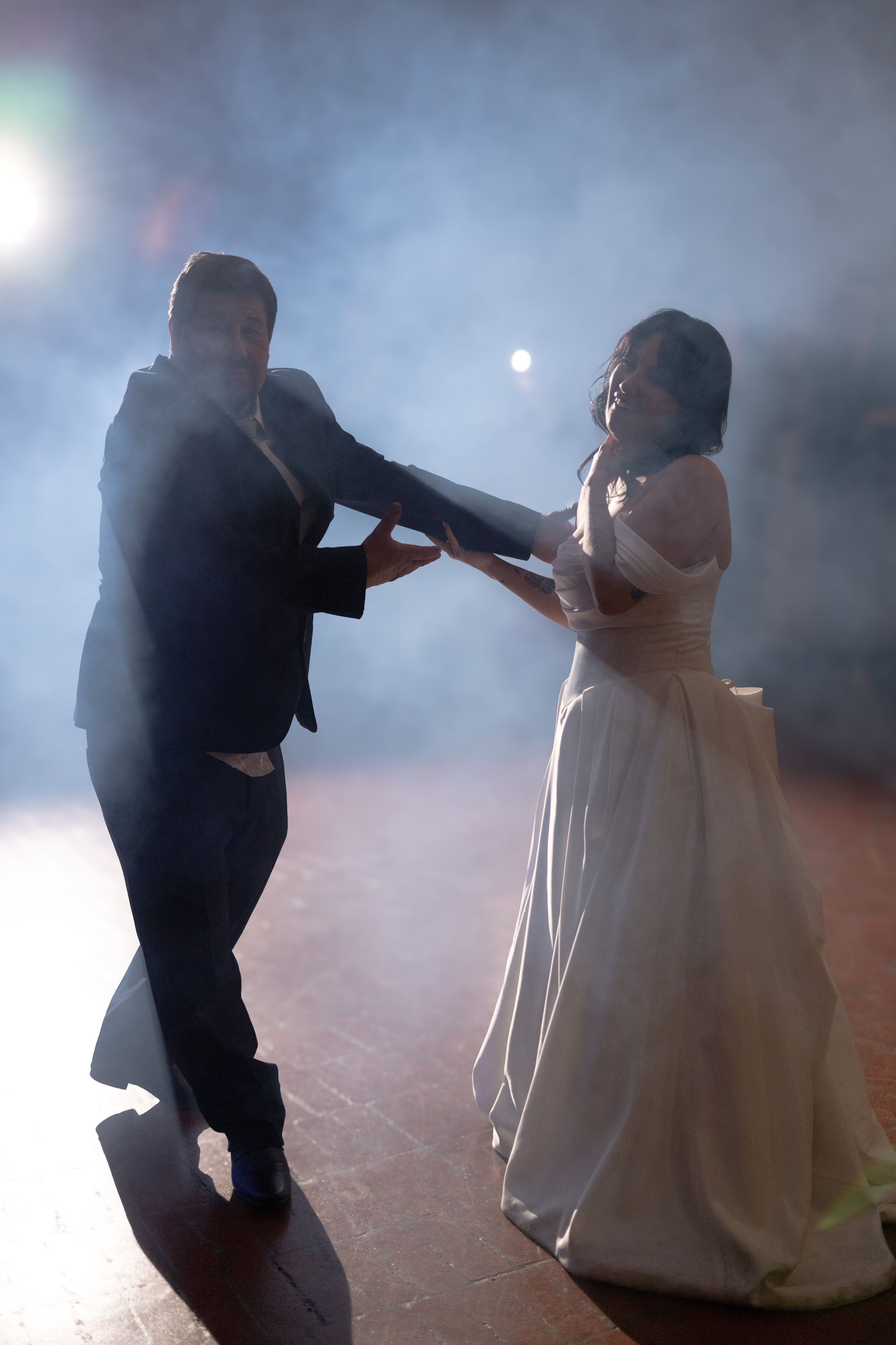A bride and groom are dancing together in a dark room.