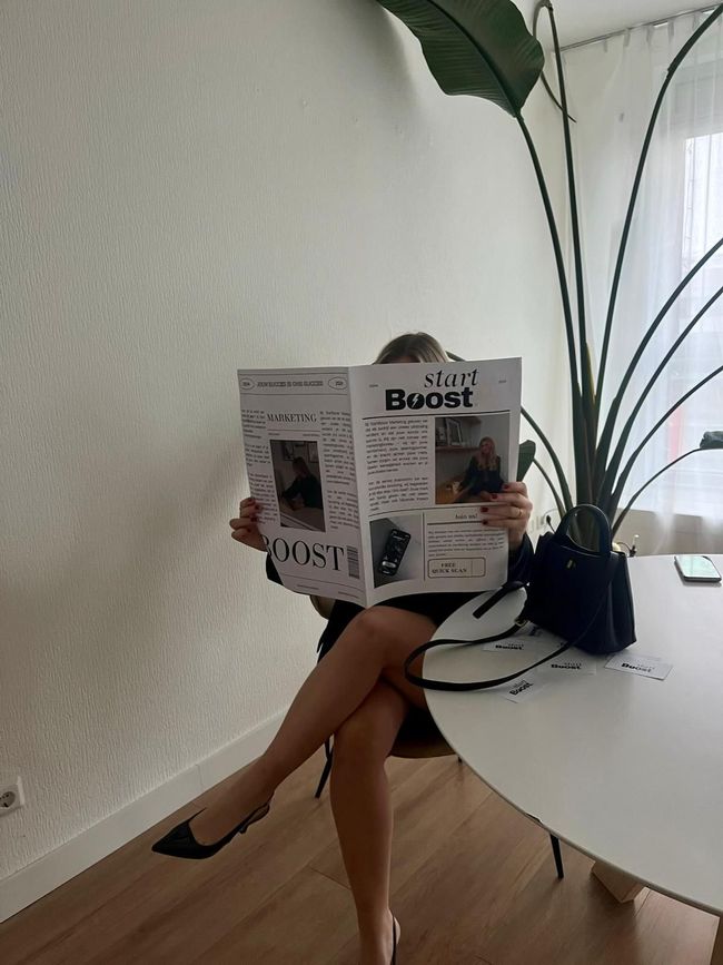 Een vrouw leest een tijdschrift genaamd start boost