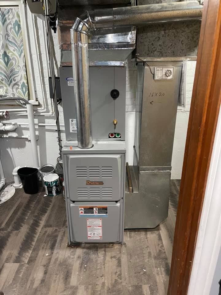 A furnace is sitting in a room next to a window.