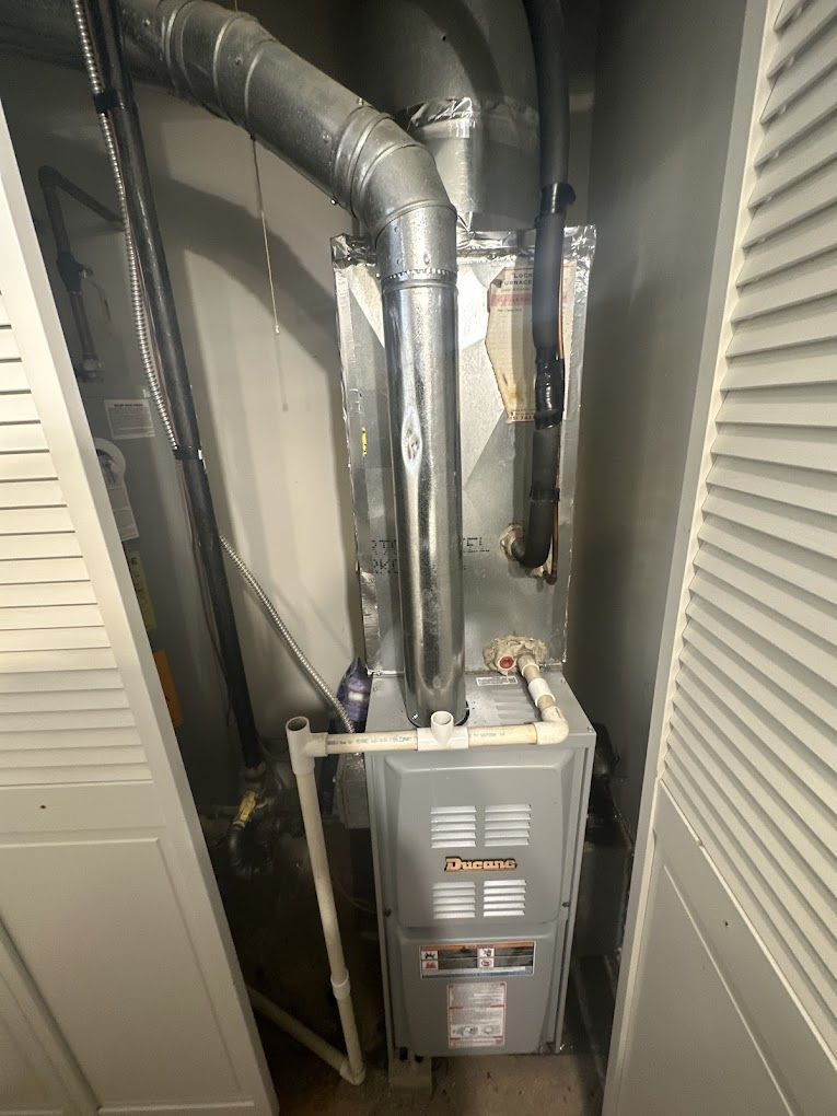 A furnace is sitting in a closet next to a wall.