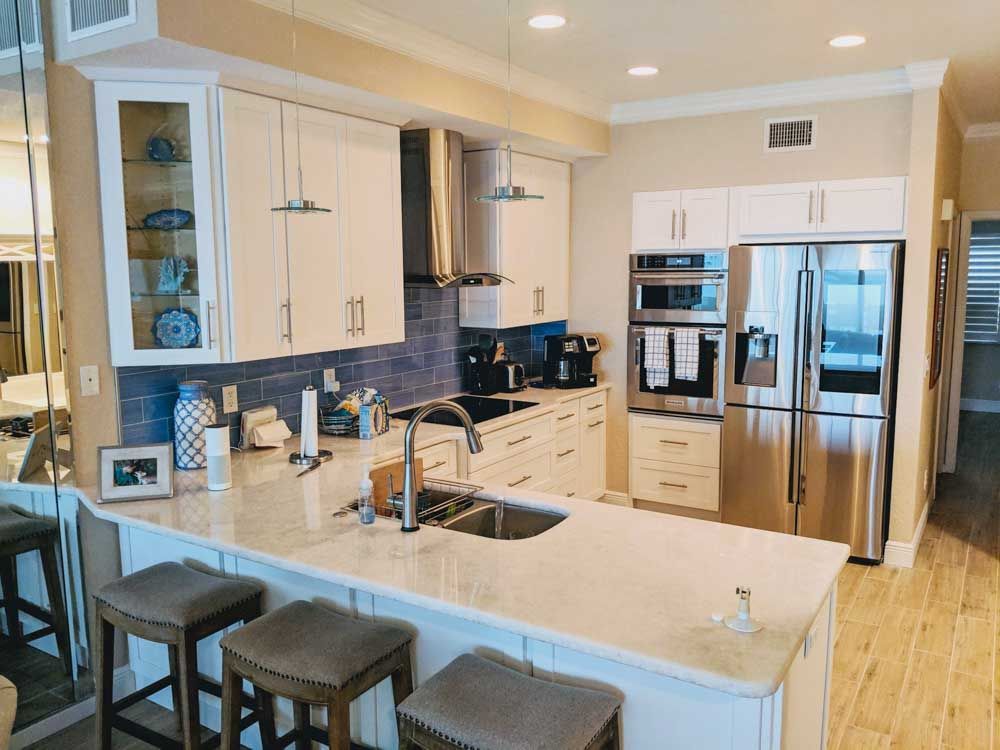 A kitchen with white cabinets , stainless steel appliances , a sink , and a refrigerator.
