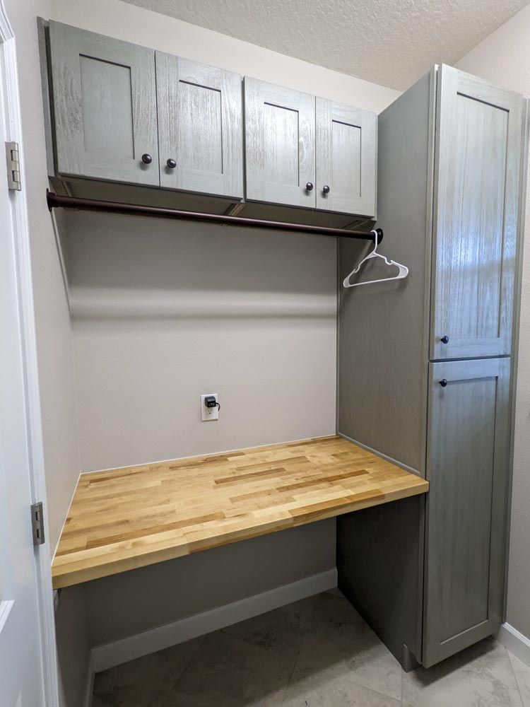 A laundry room with a wooden desk and cabinets.