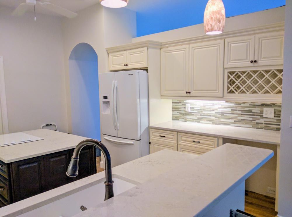 A kitchen with white cabinets and a white refrigerator.