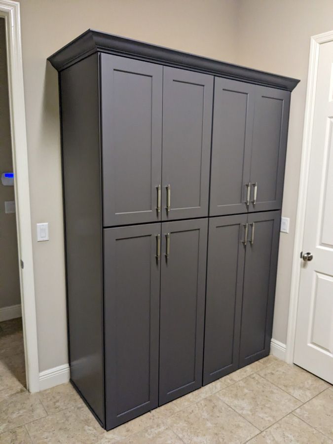 A large gray cabinet is sitting in a room next to a door.