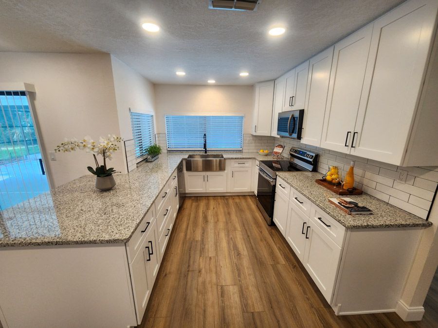A kitchen with white cabinets and granite counter tops.