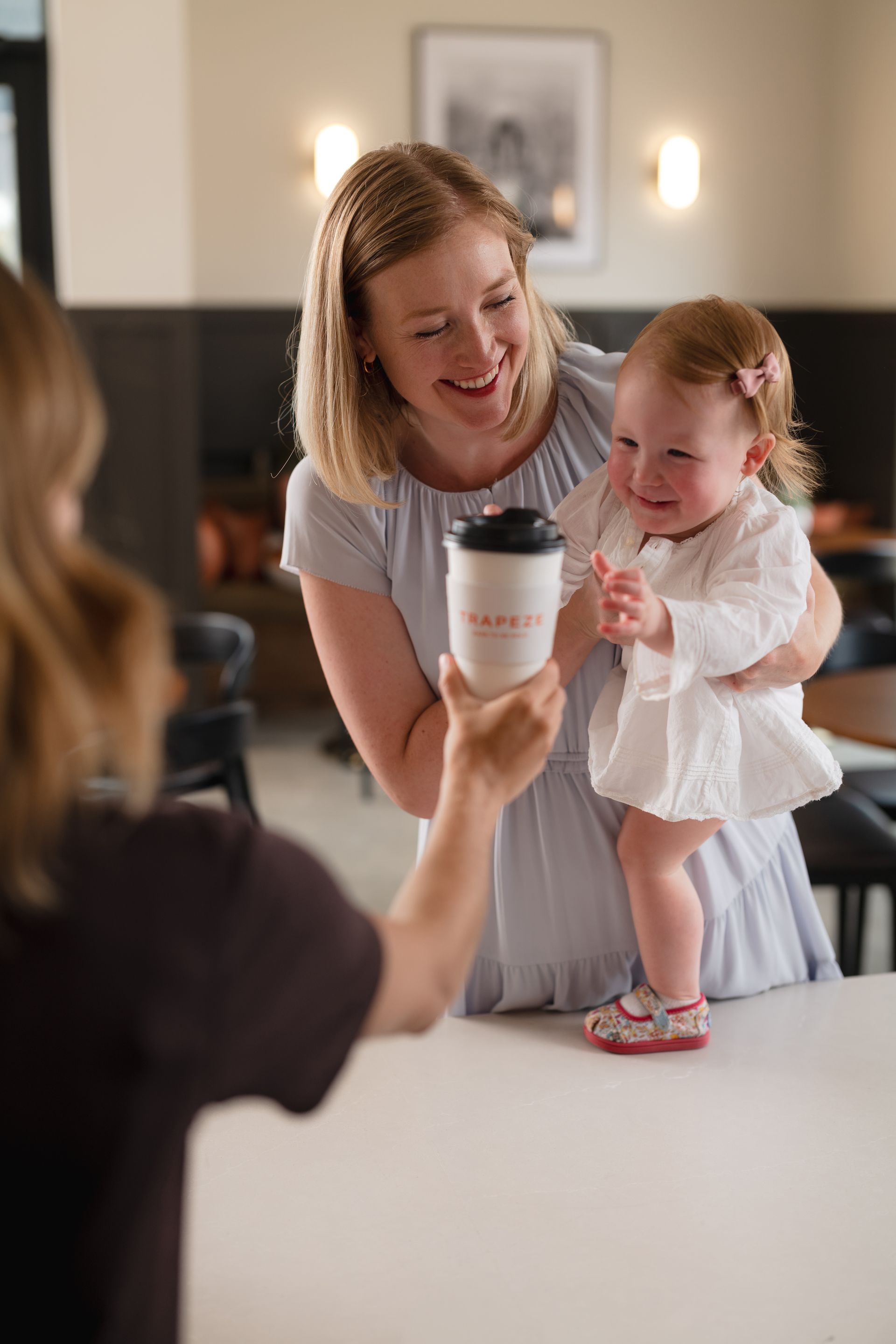 Women with her baby holding a coffee cup.
