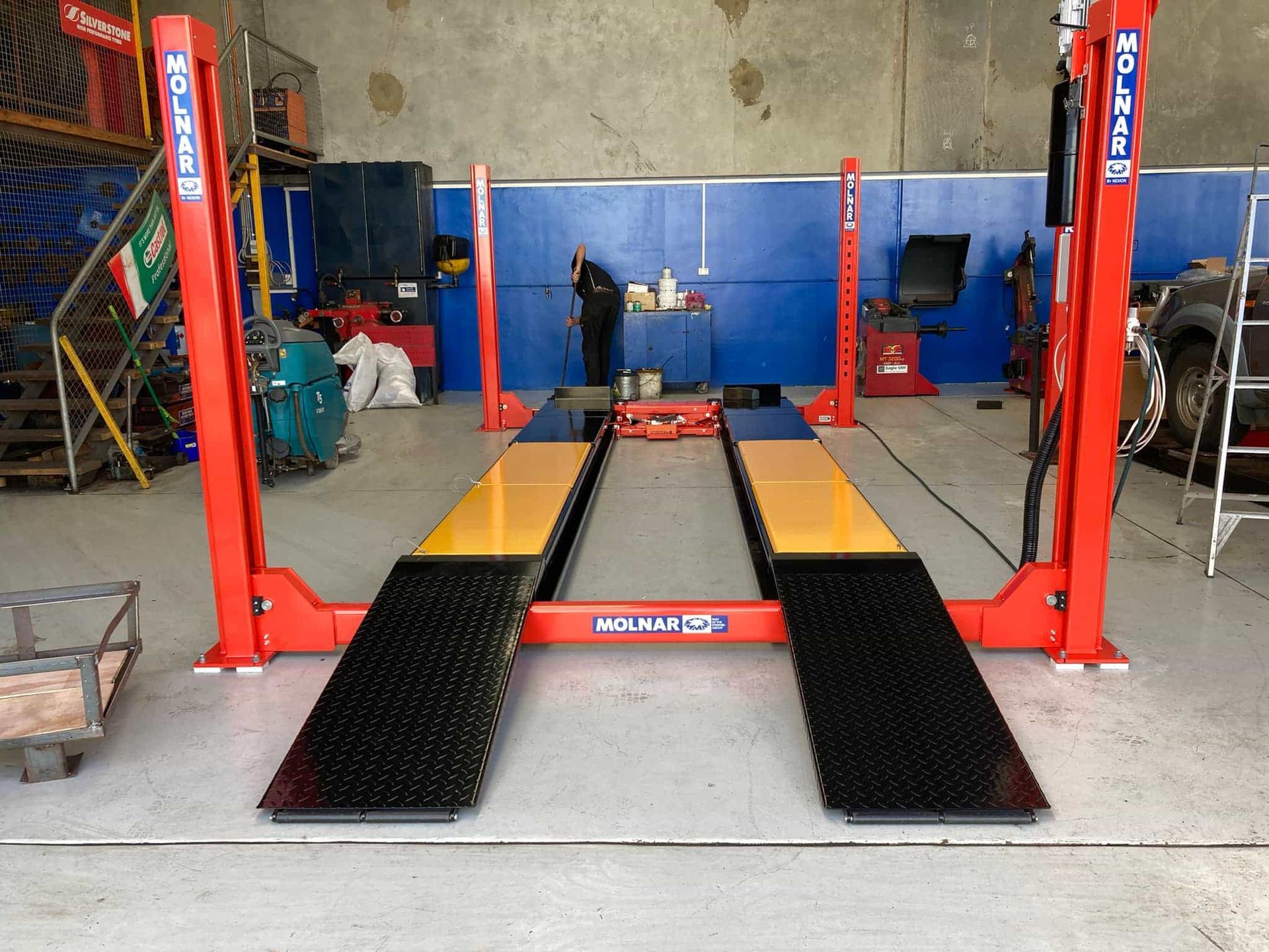 A red and yellow car lift in a garage — Pialba Brake Clutch & Steering in Pialba, QLD
