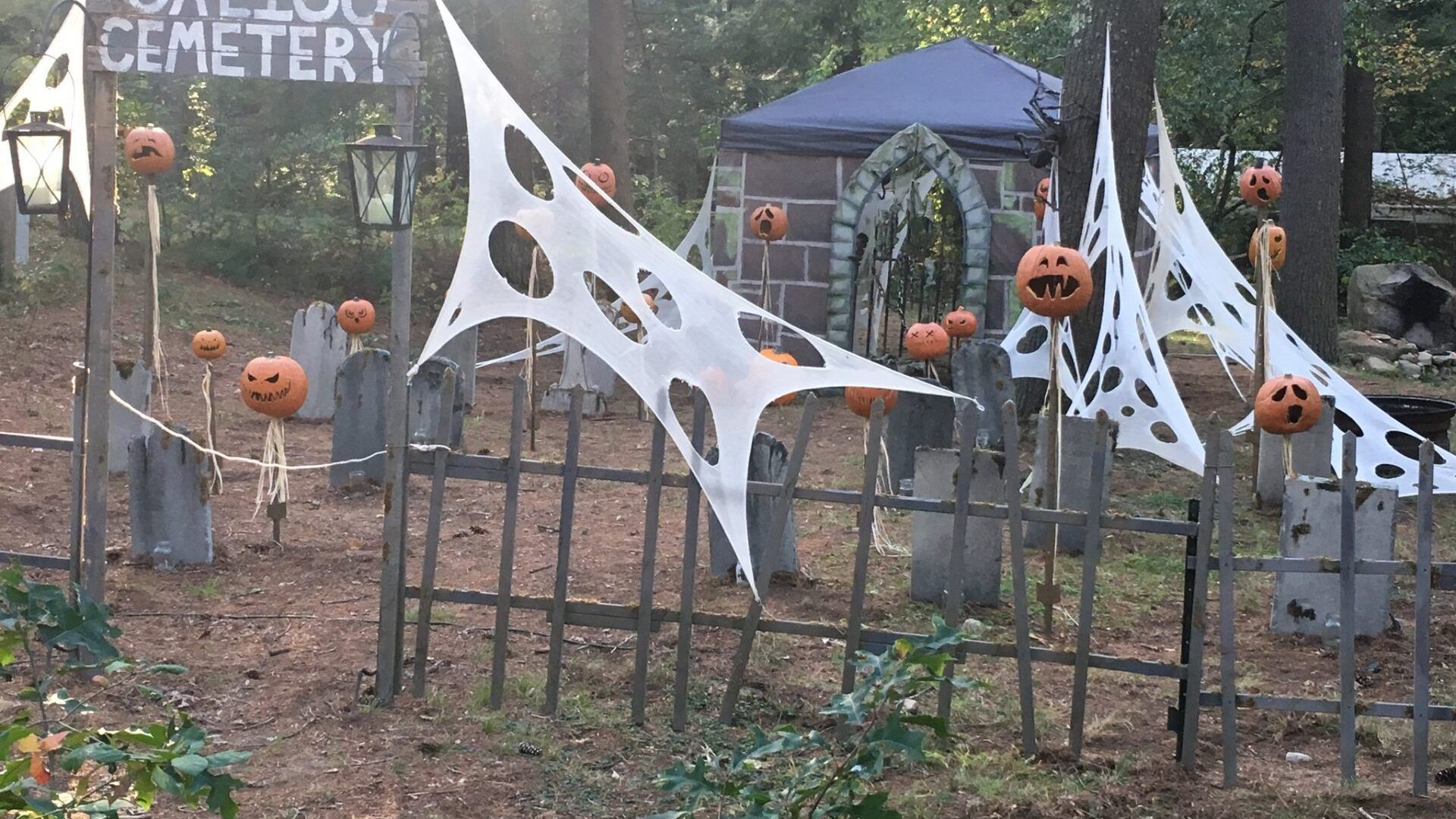 A cemetery is decorated for halloween with pumpkins and spider webs