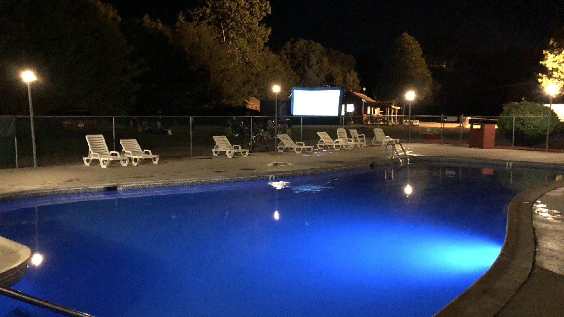 A large swimming pool is lit up at night.