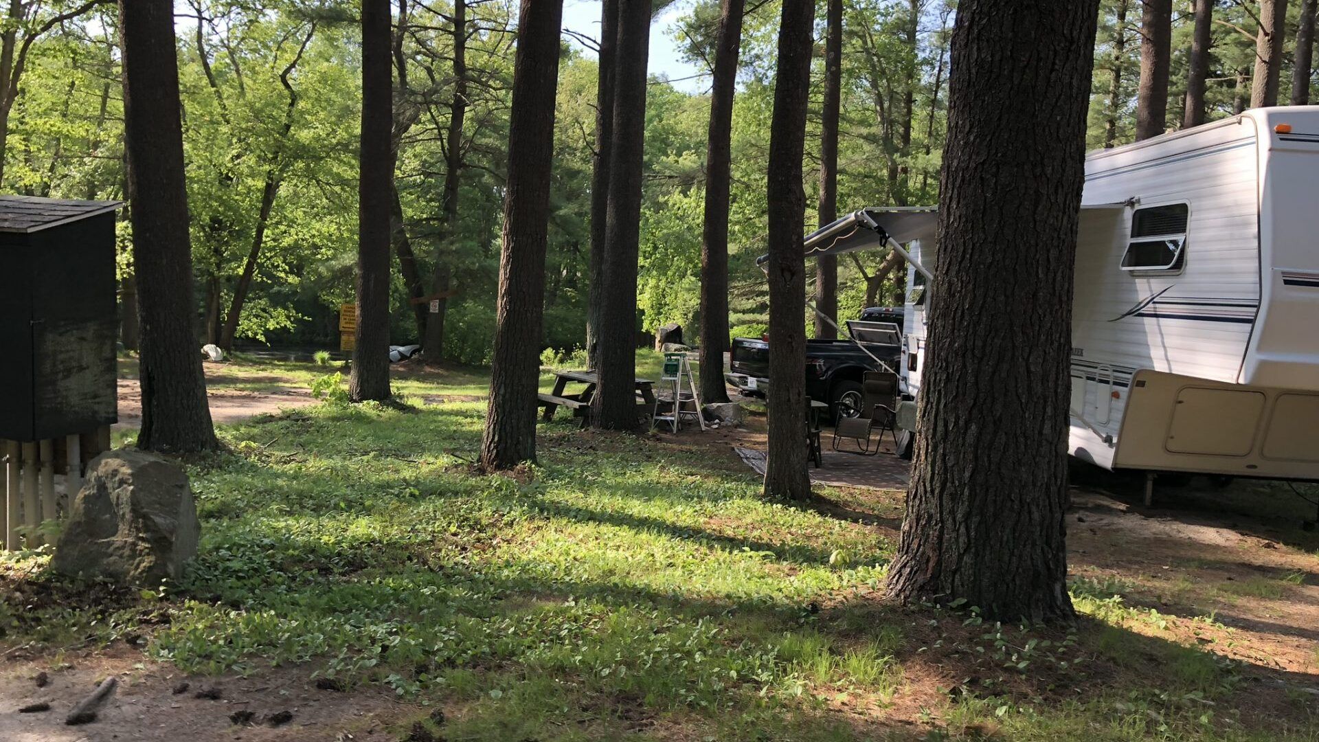A rv is parked in the middle of a forest.
