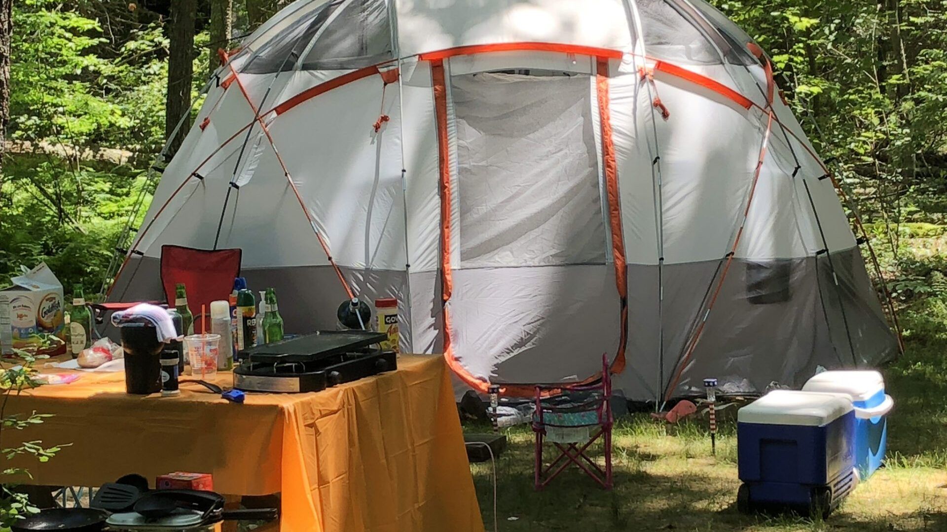A large tent is sitting in the middle of a field next to a table and chairs.