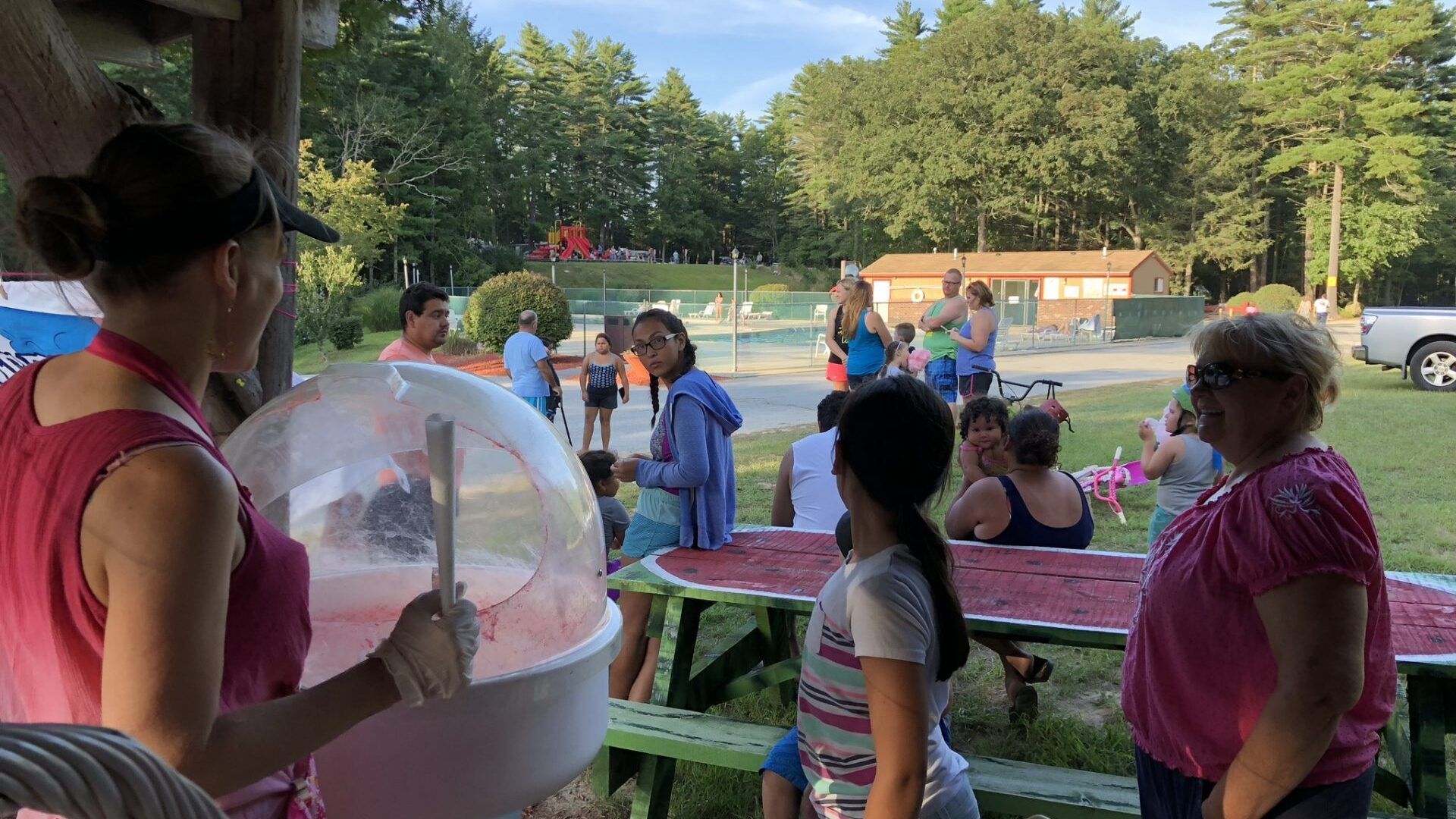 A woman is selling cotton candy at a picnic table.