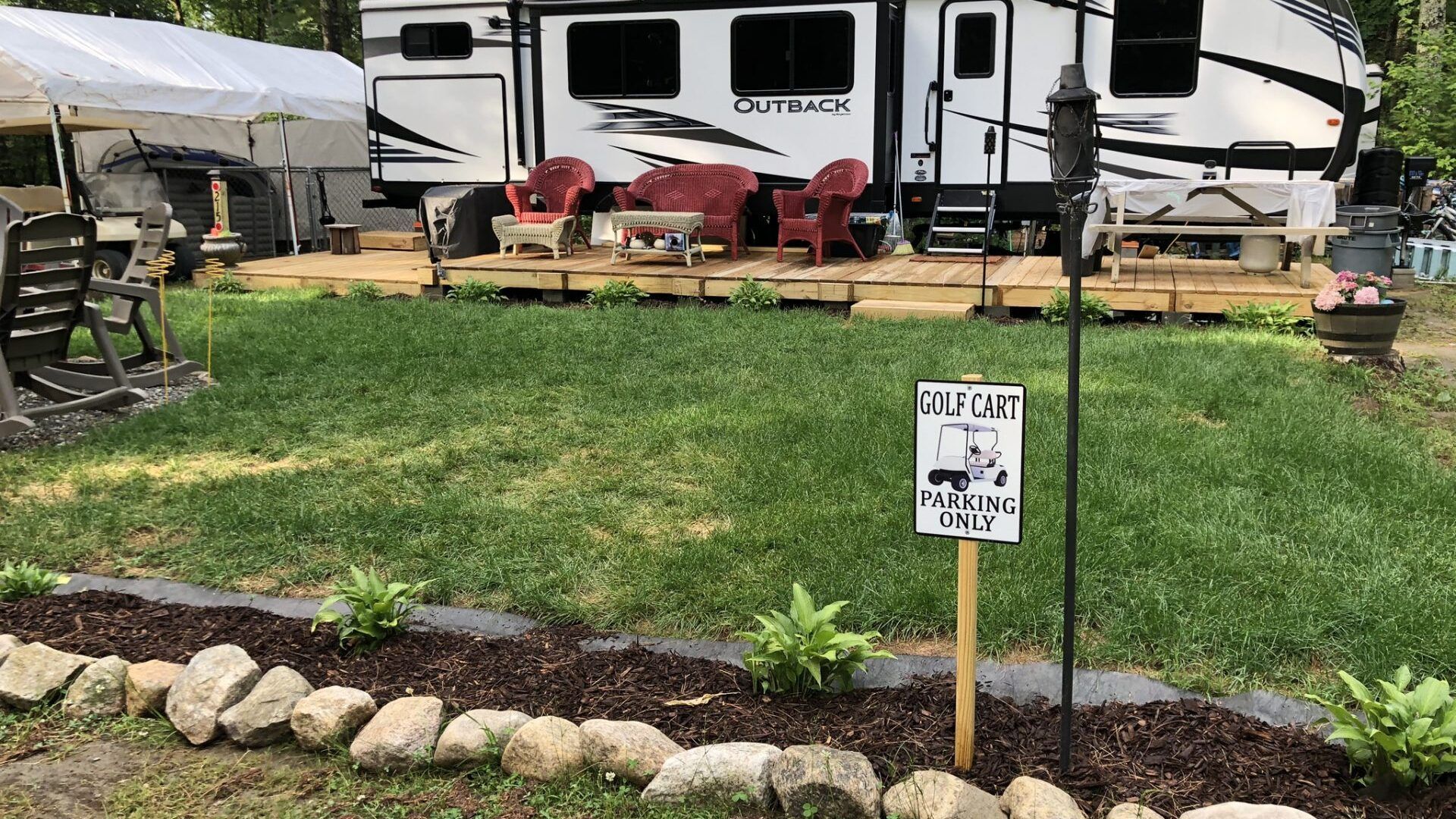 A rv parked in a grassy yard with a sign in front of it.