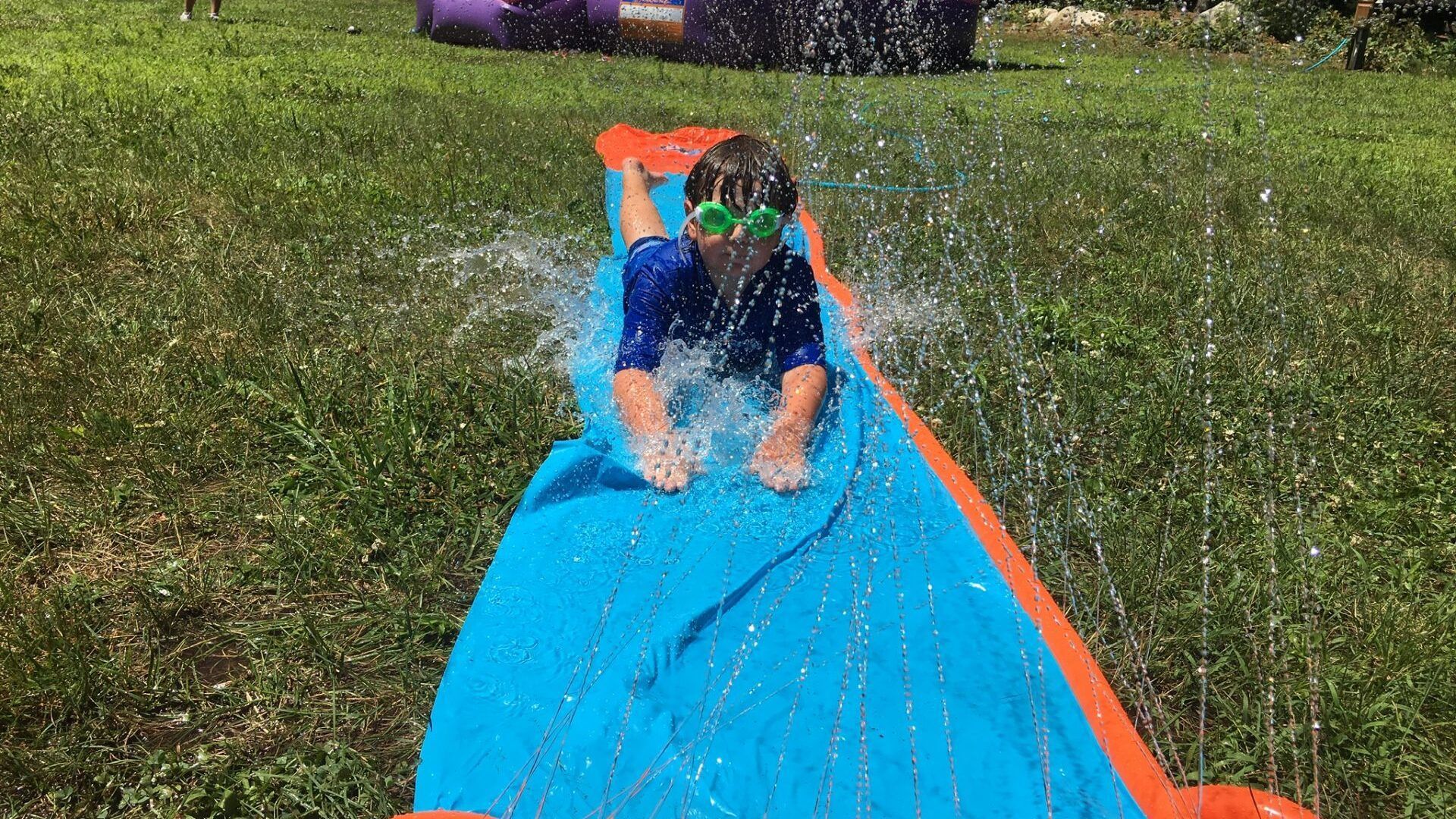 A young boy is sliding down a water slide.