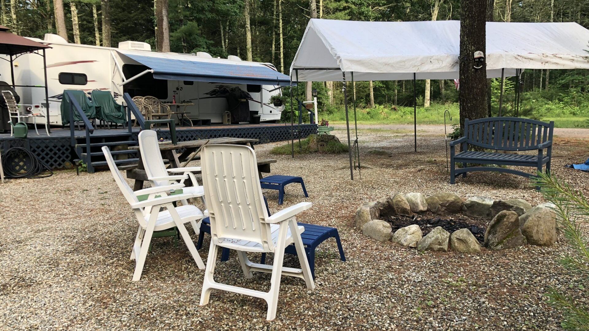 A group of chairs are sitting around a fire pit in front of a rv.