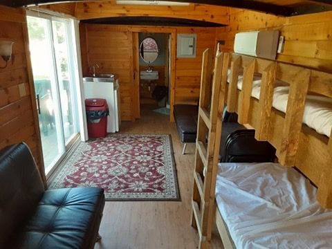 A wooden cabin with bunk beds , a couch , and a sink.