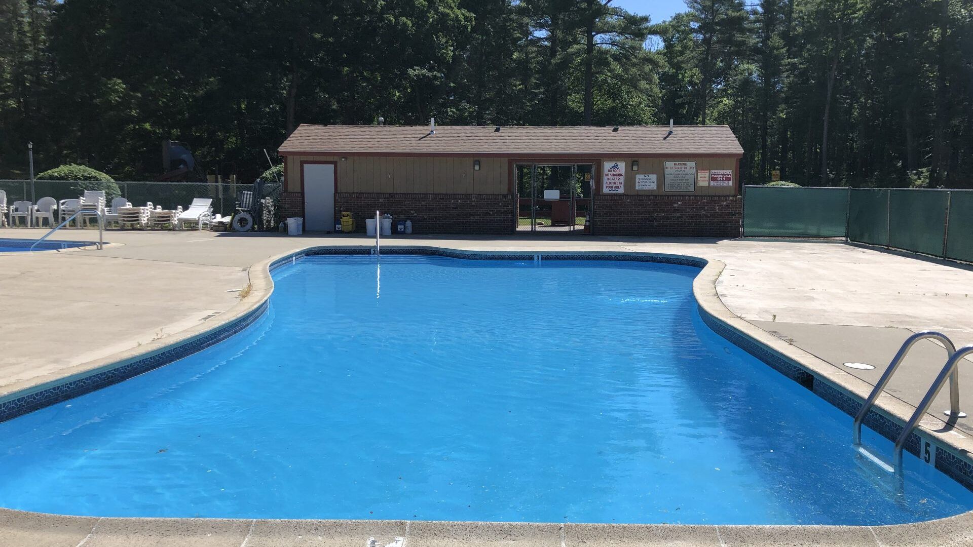 A large swimming pool with a small building in the background.