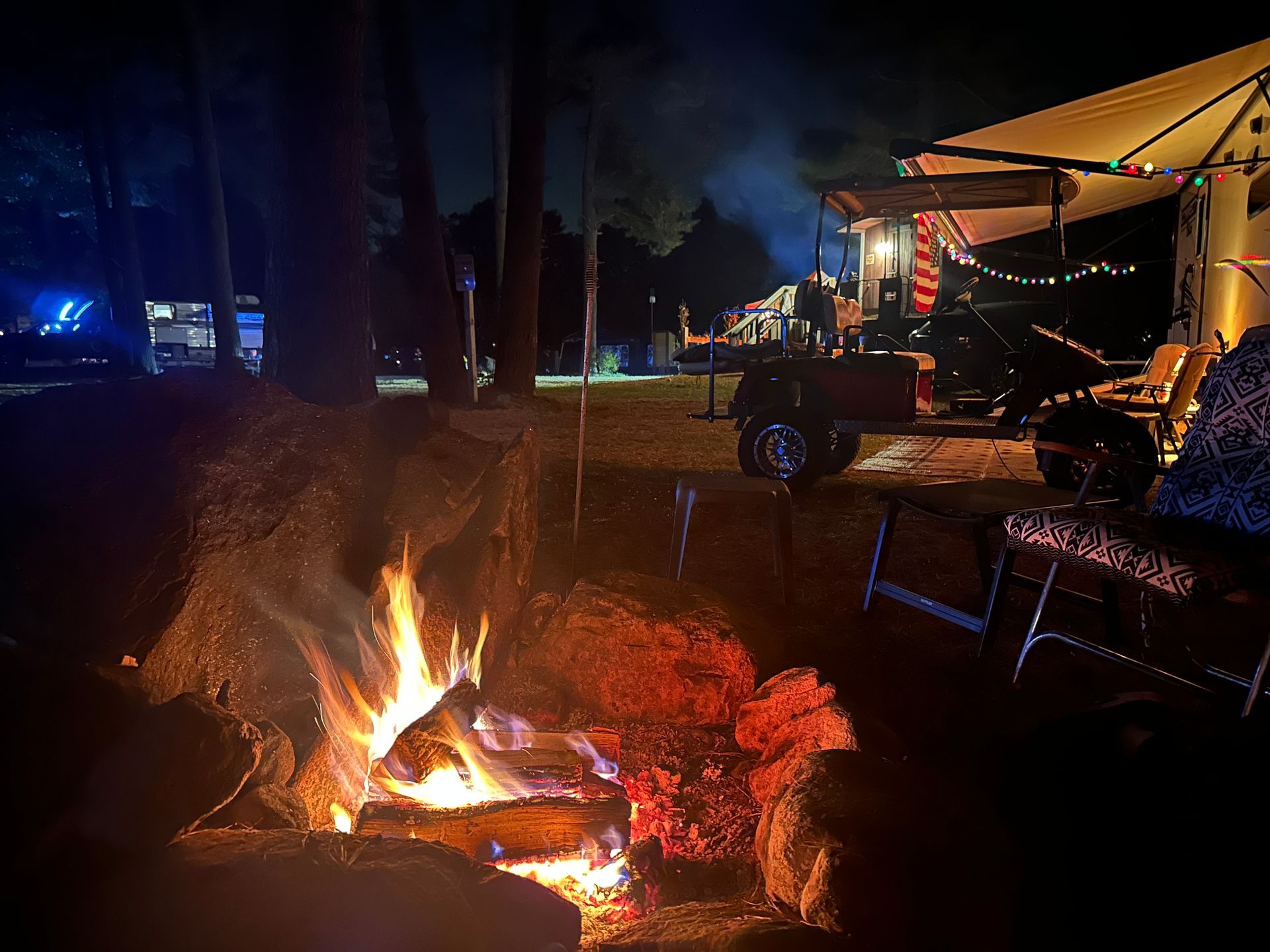 A campfire is lit up in the middle of a forest at night.