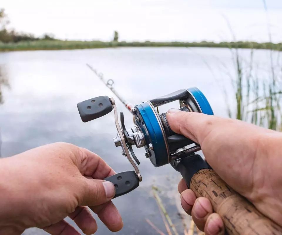 A person is holding a fishing rod and reel in their hands.