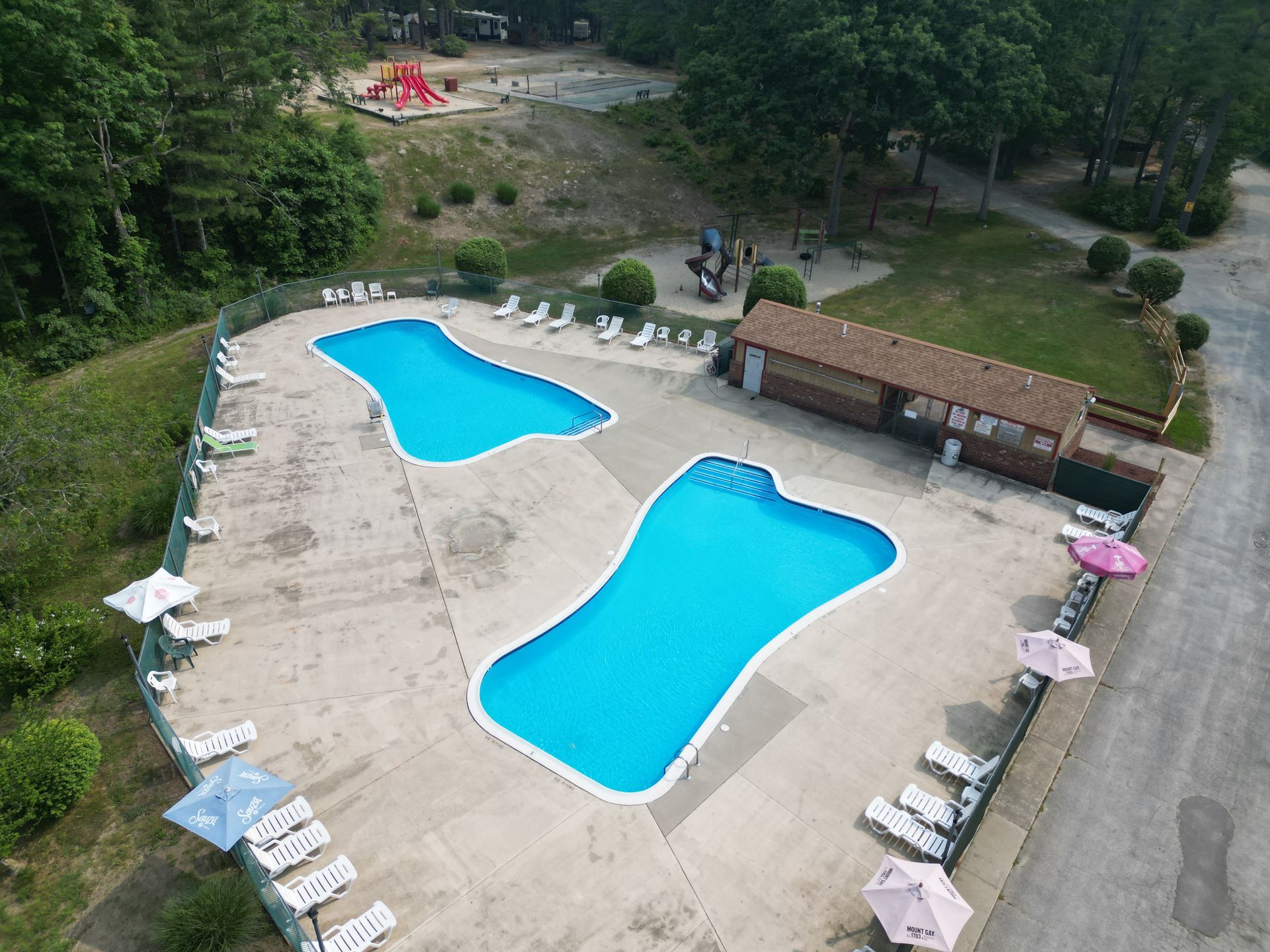 An aerial view of two swimming pools surrounded by chairs and umbrellas.