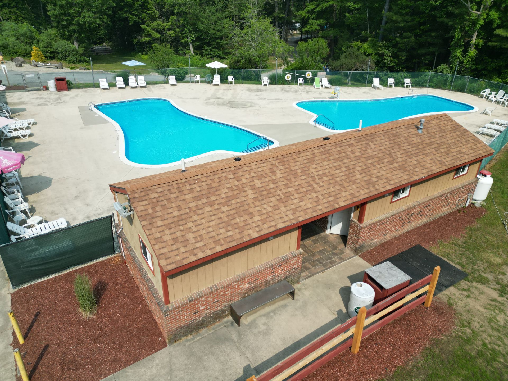 An aerial view of a swimming pool with a brick building in the foreground.