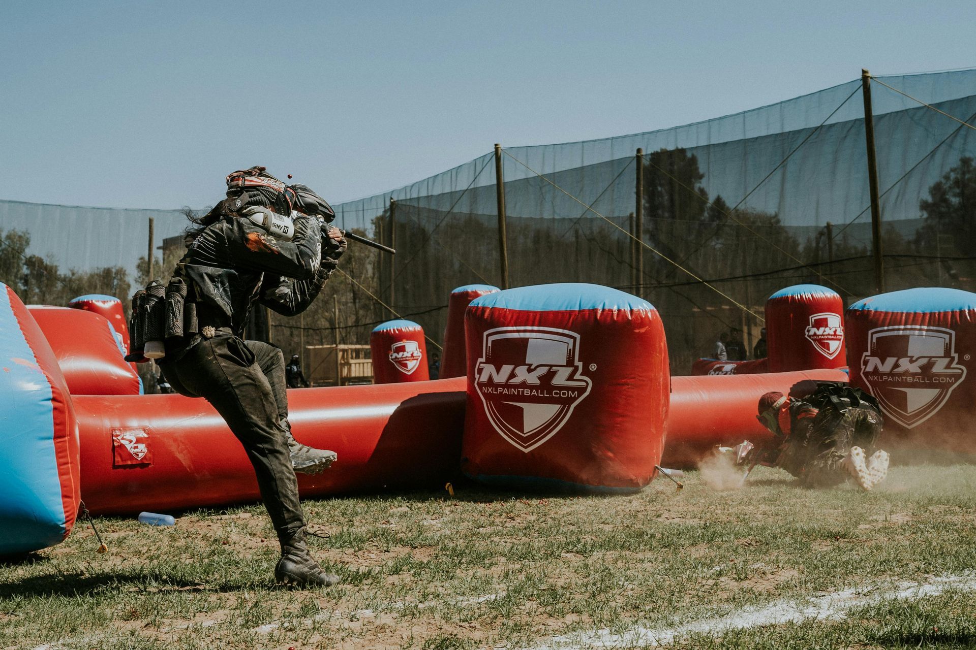 A man is playing paintball on an inflatable field.