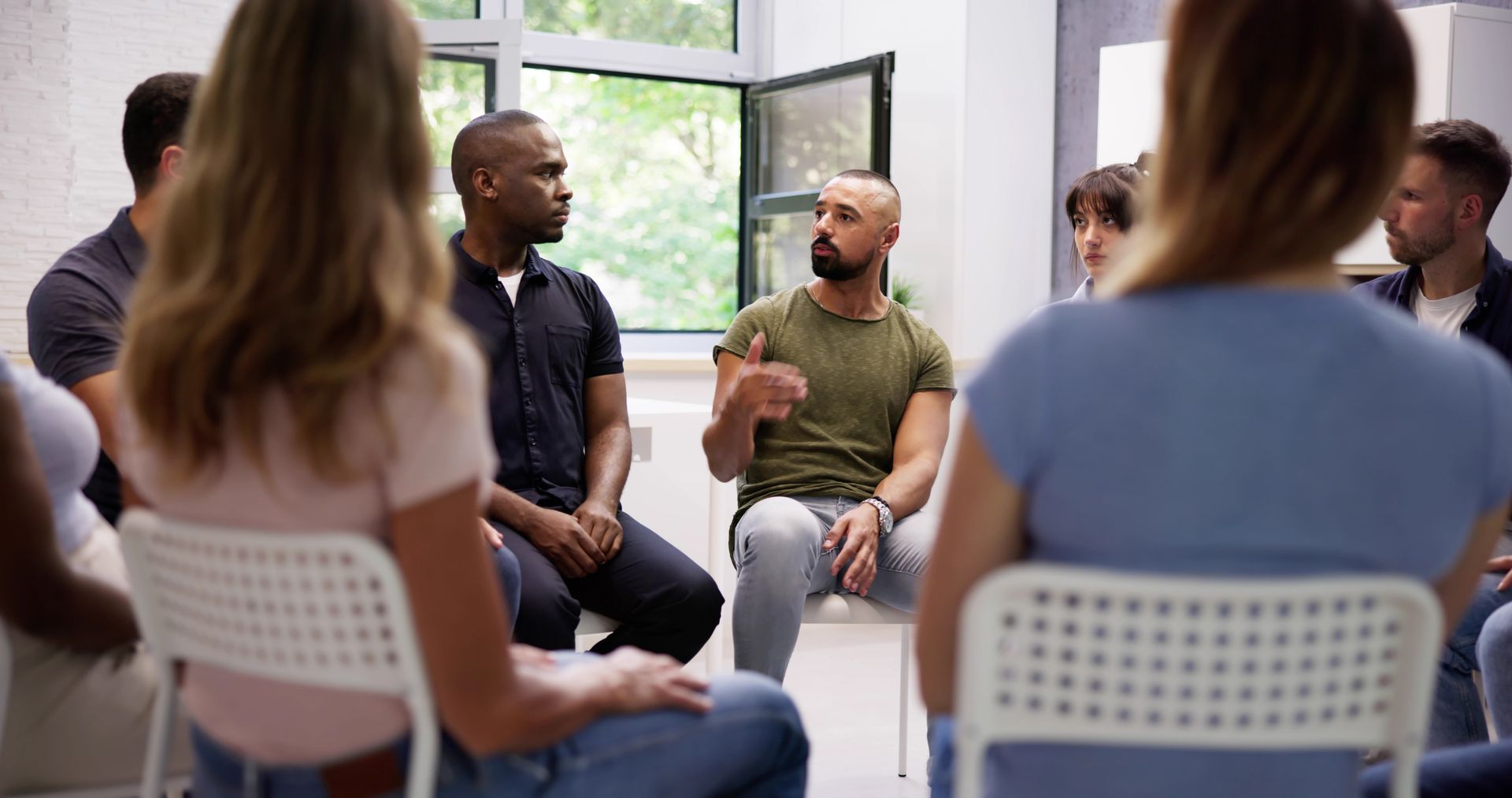 Group therapy session: People in a circle, one man gestures while speaking.