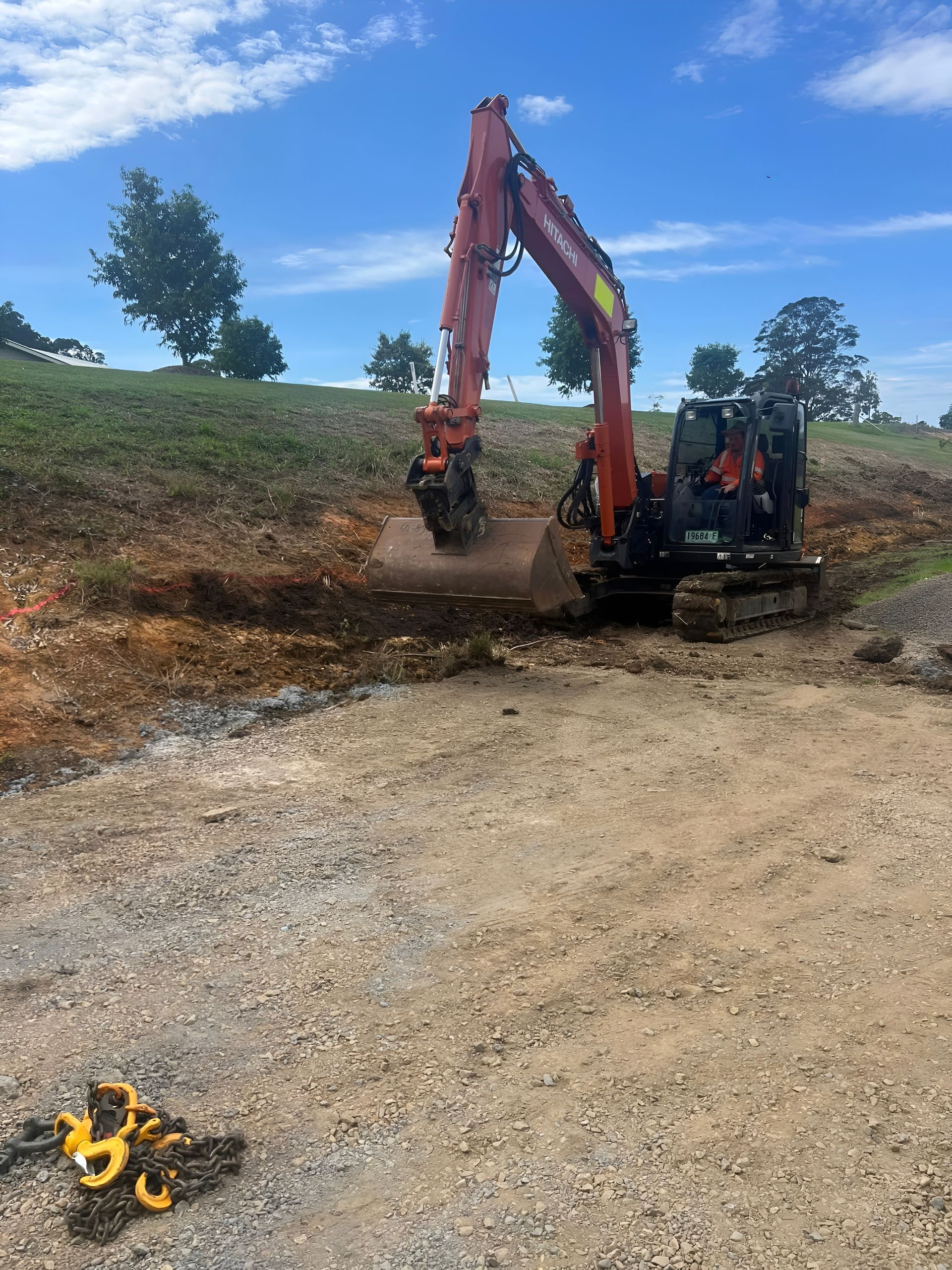Red Excavator Digging in Dirt Next to a Gravel Driveway — MG Earthworks and Plant Hire in Bellingen, NSW