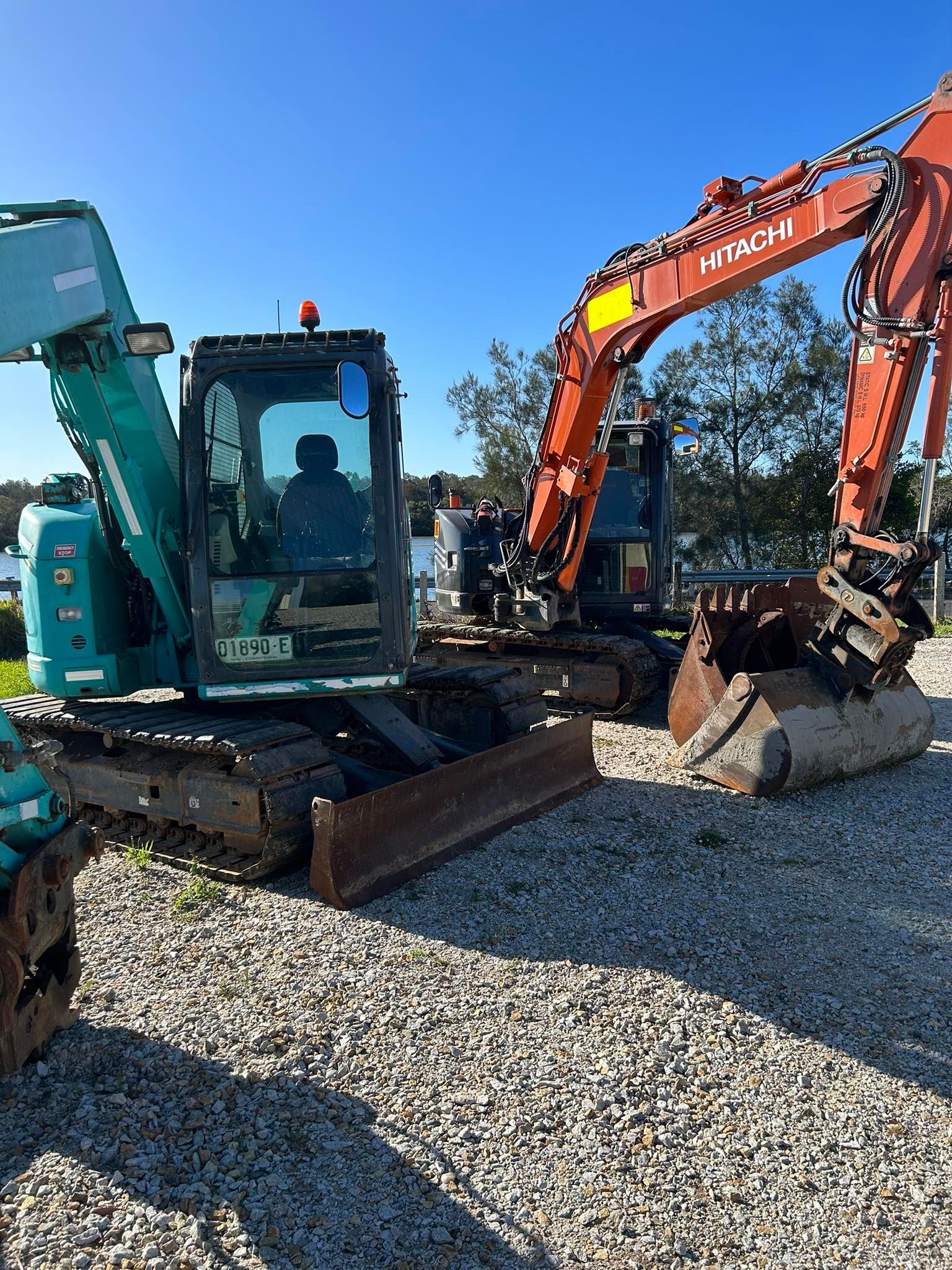 A Teal and Orange Excavator on Gravel, Under a Blue Sky — MG Earthworks and Plant Hire in Gumma, NSW